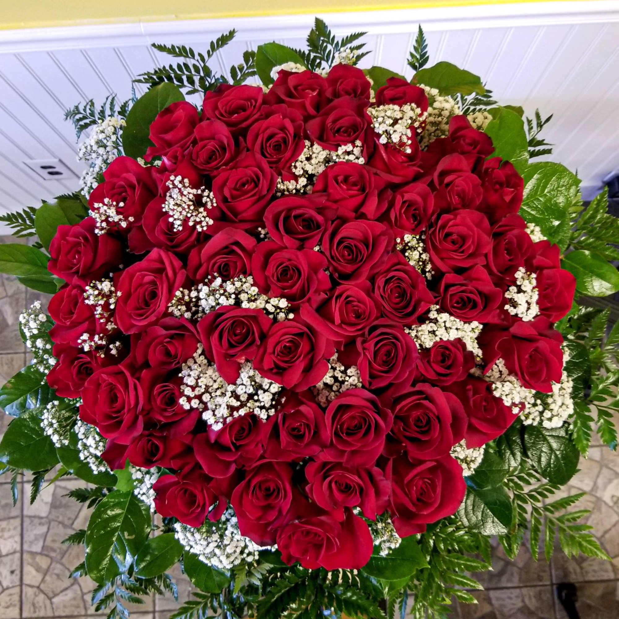 Large bouquet of red roses with white filler flowers and greenery