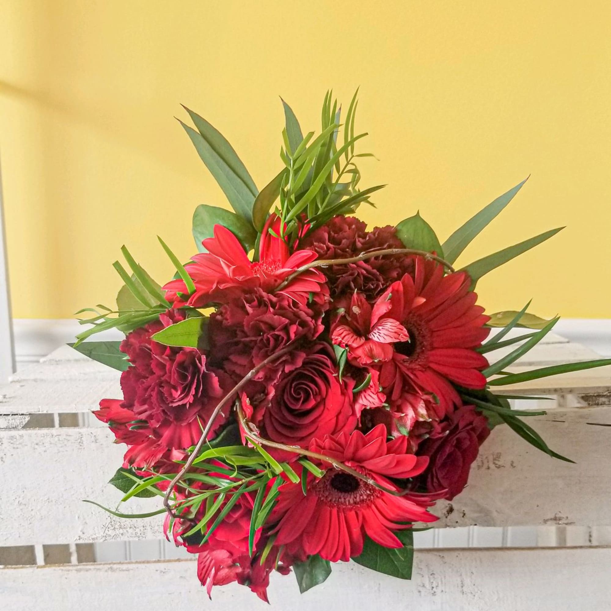 Red gerbera daisies and roses arranged in a compact bouquet