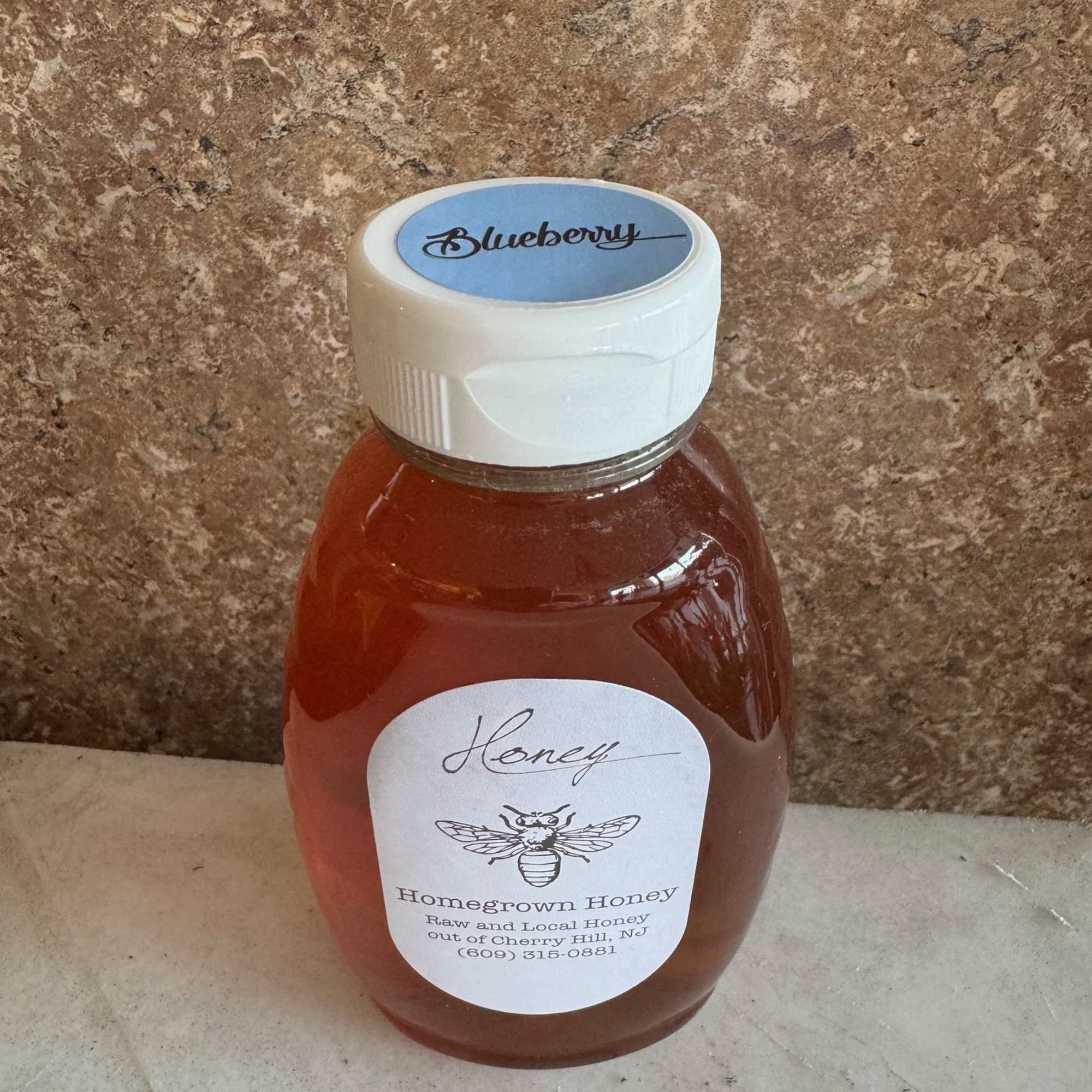 A plastic bottle of blueberry honey with a white cap
