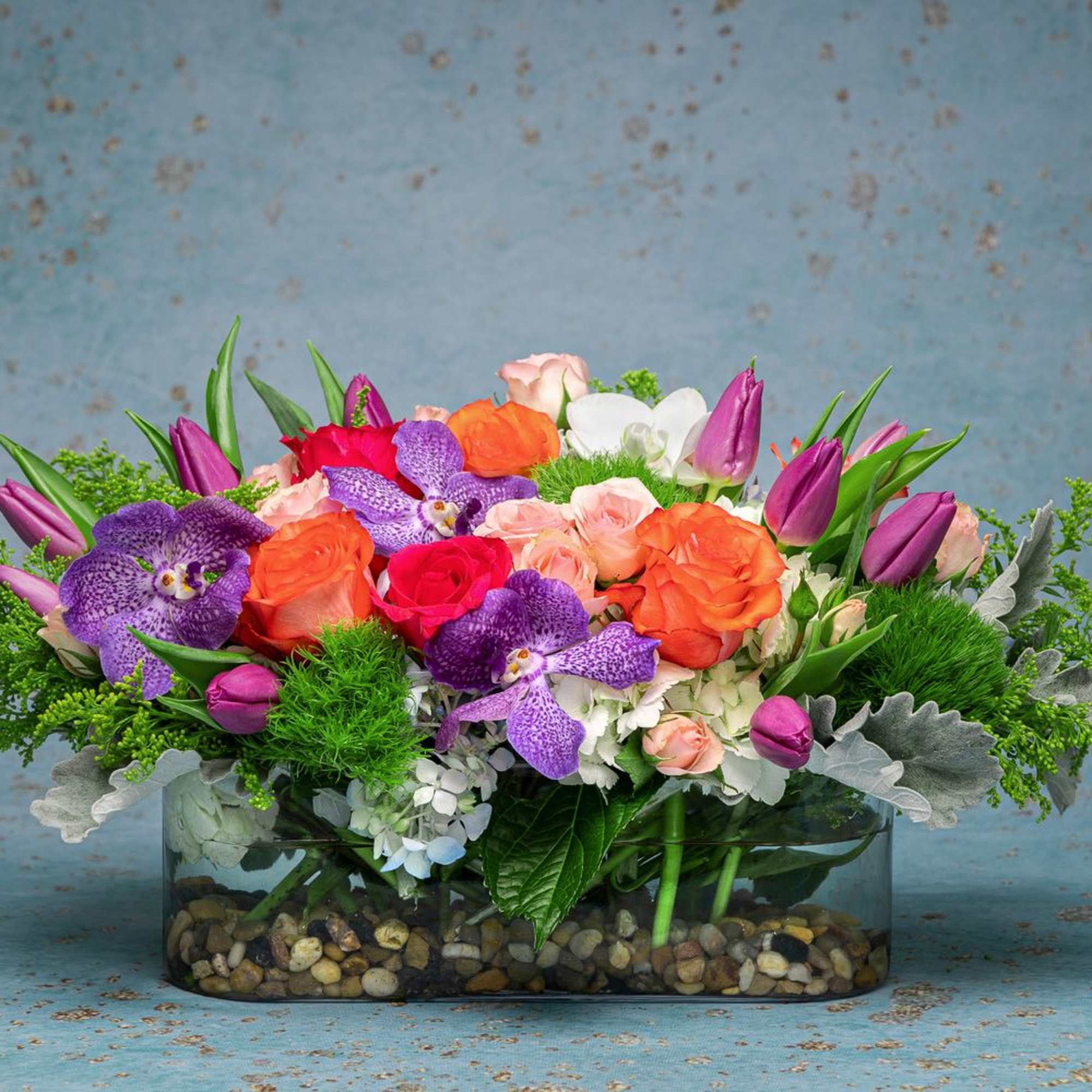 Colorful mixed bouquet in a low glass vase with pebbles