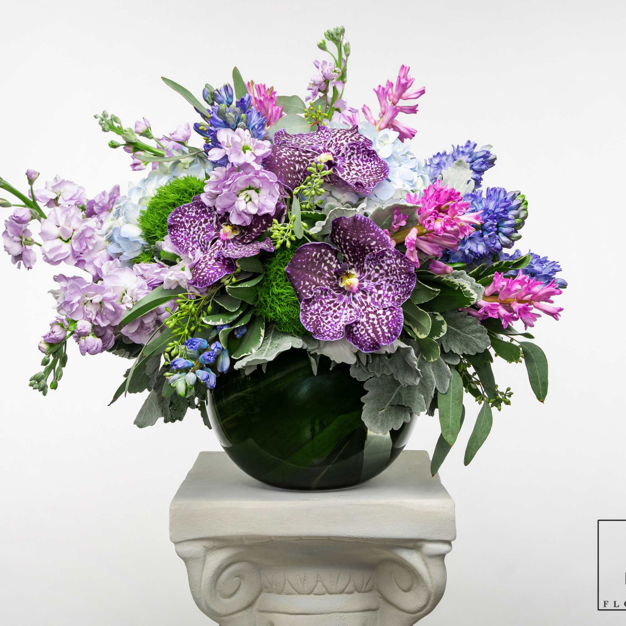 Mixed purple and blue flowers arranged in a dark glass vase