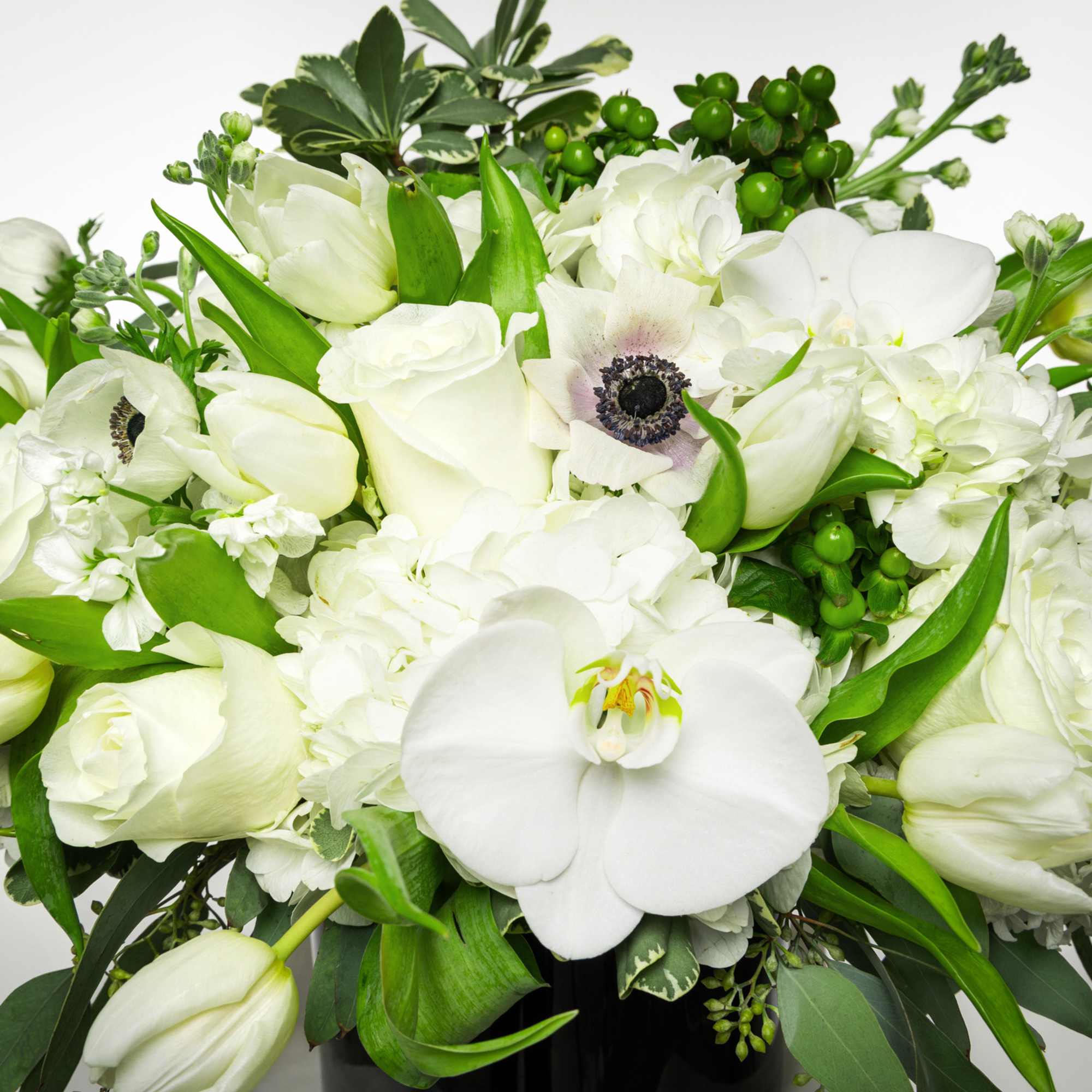 White floral arrangement with orchids, tulips, and anemones