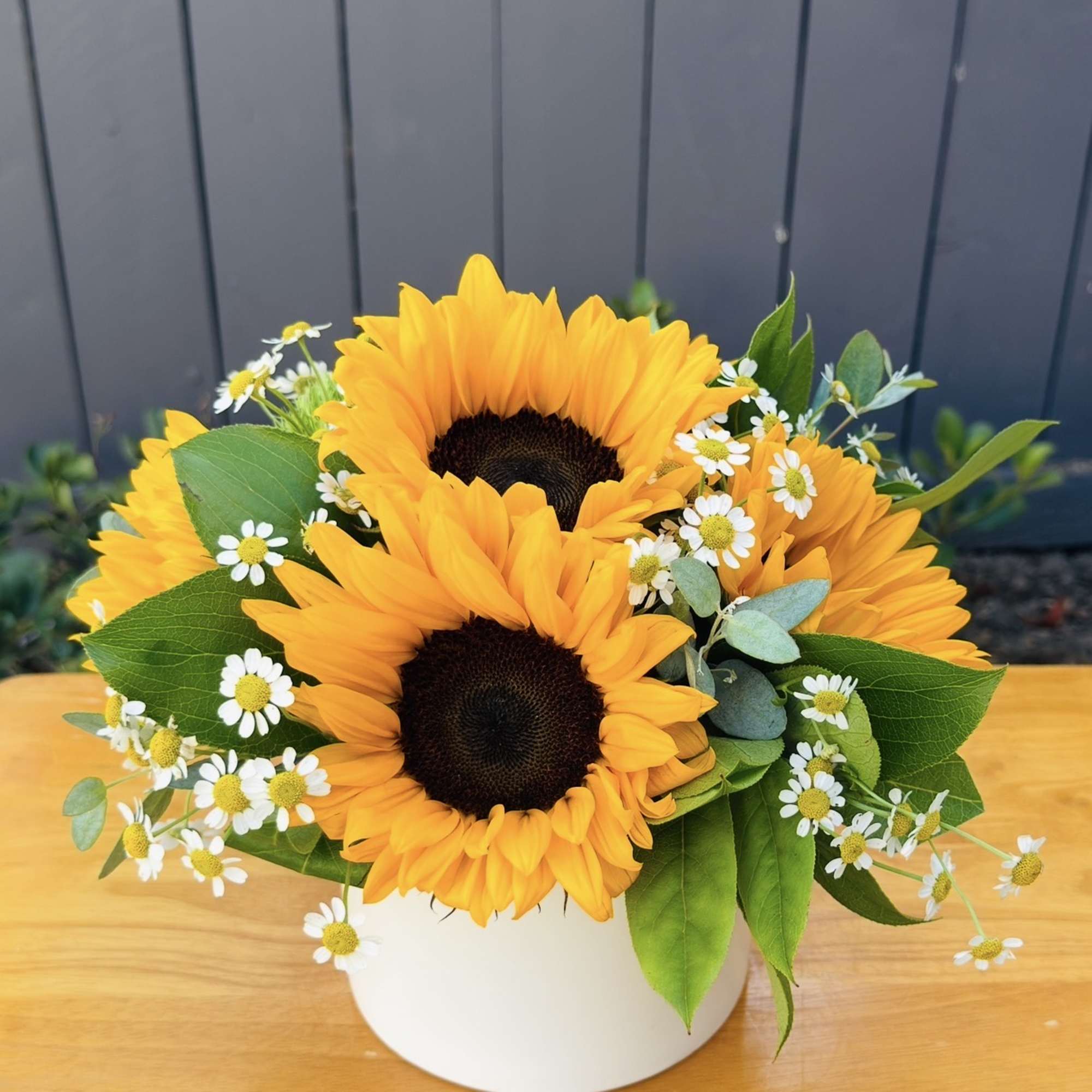 Sunflower bouquet in a white vase with small white daisies
