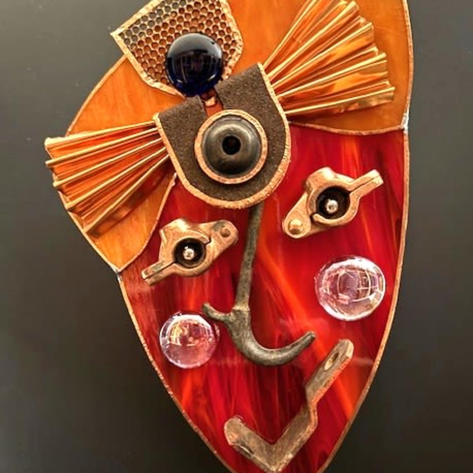 A striking red-and-orange stained glass wall mask that reads like a modern