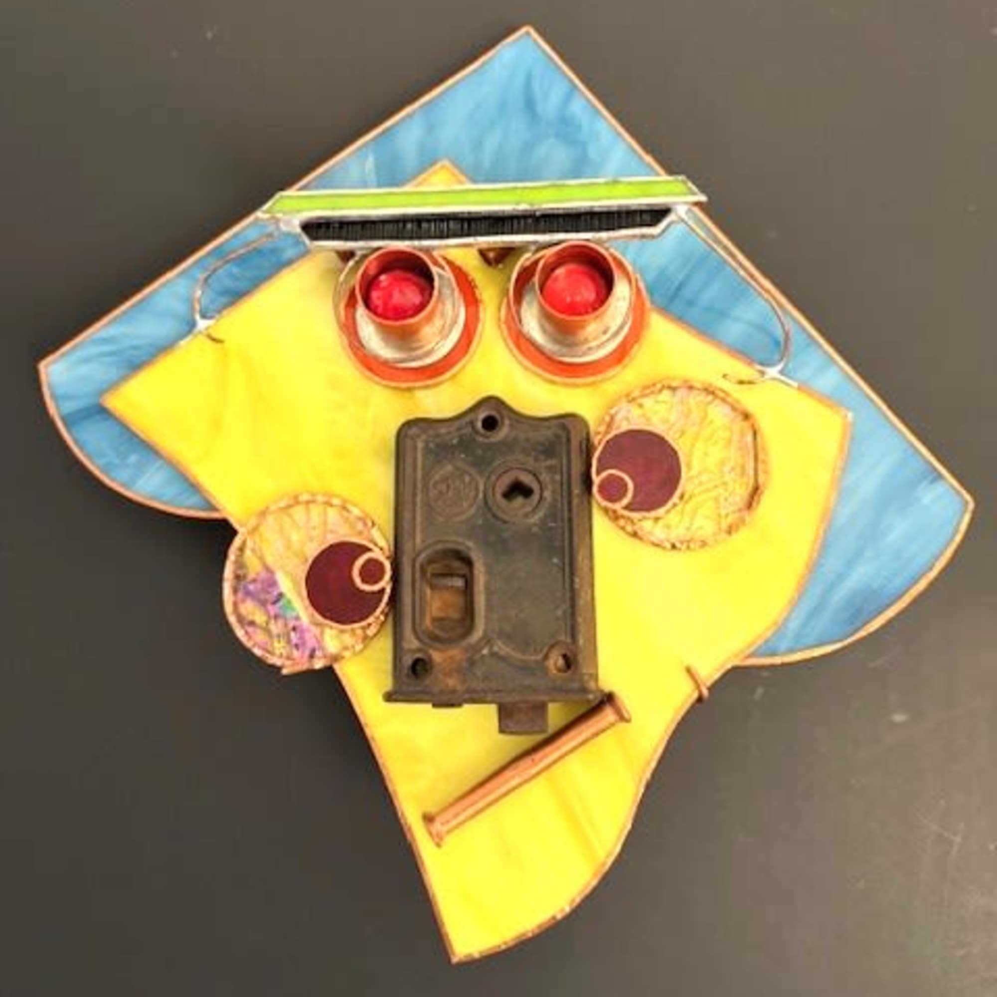 A geometric, upcycled wall sculpture that reads like a playful portrait-this mask