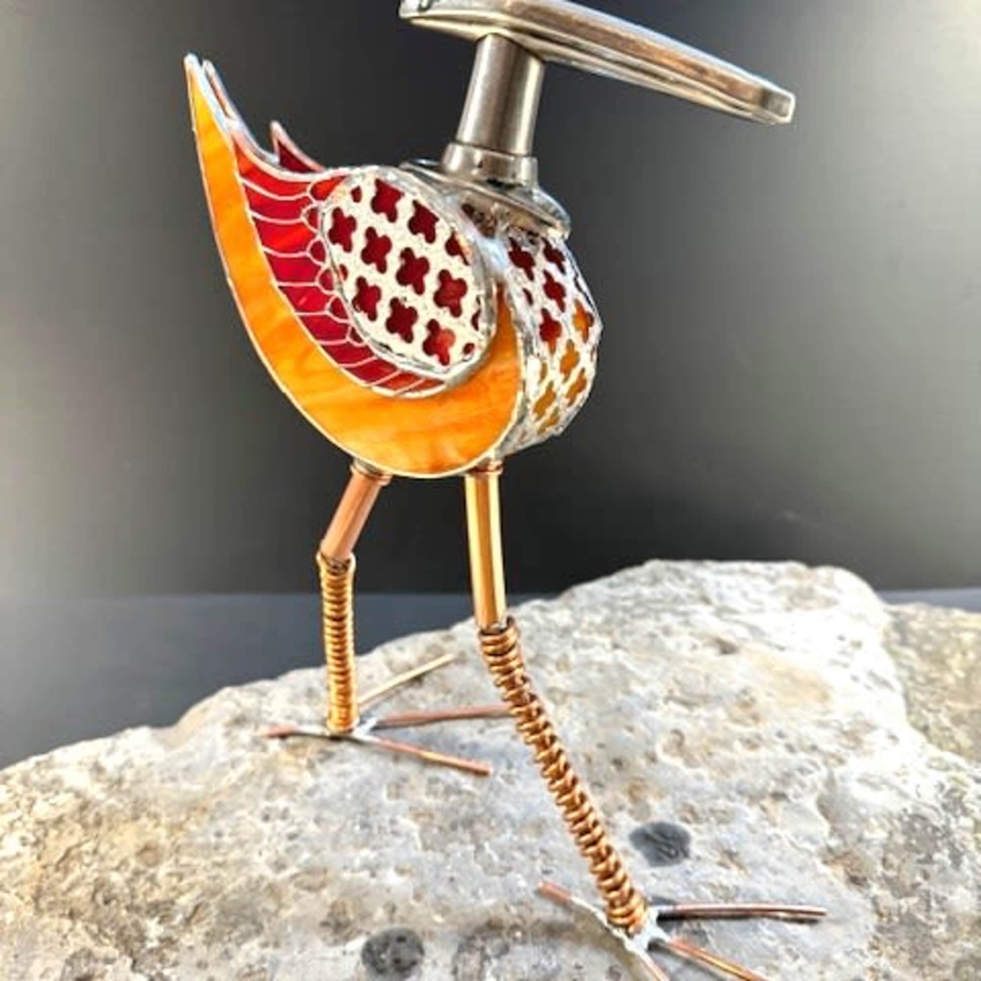 A playful metal-and-glass bird that reads like a museum sculpture and a