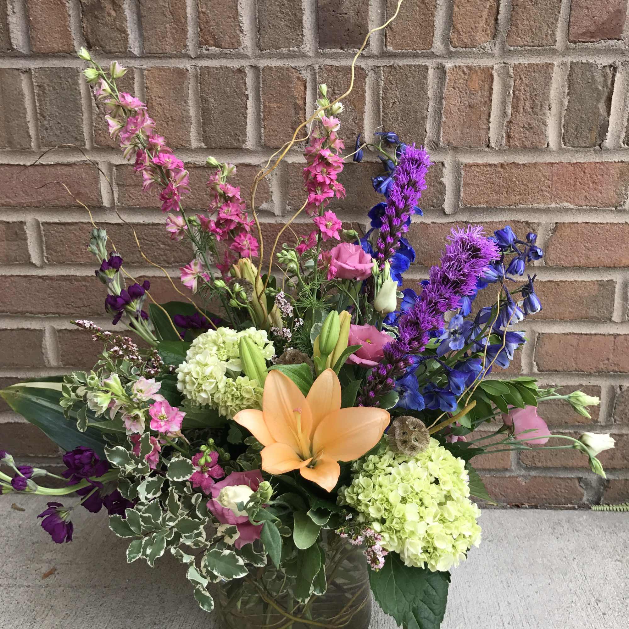 Mixed bouquet in a glass vase with orange lily, pink and purple flowers