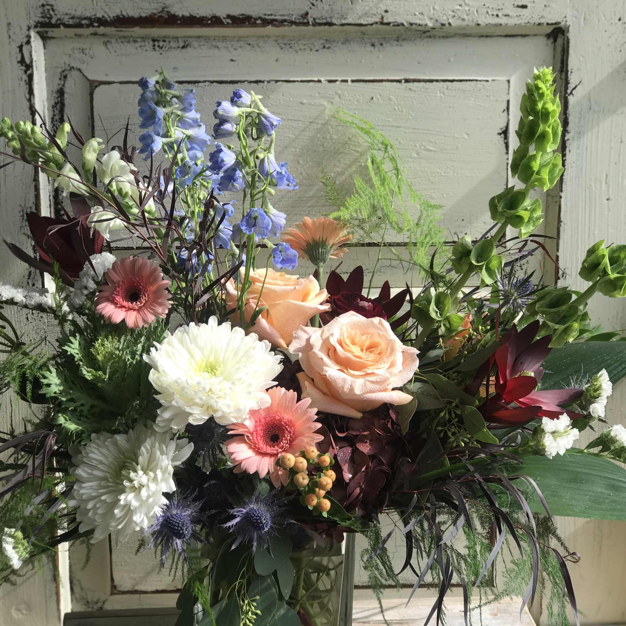 Mixed bouquet with peach roses, white chrysanthemums, and blue delphinium