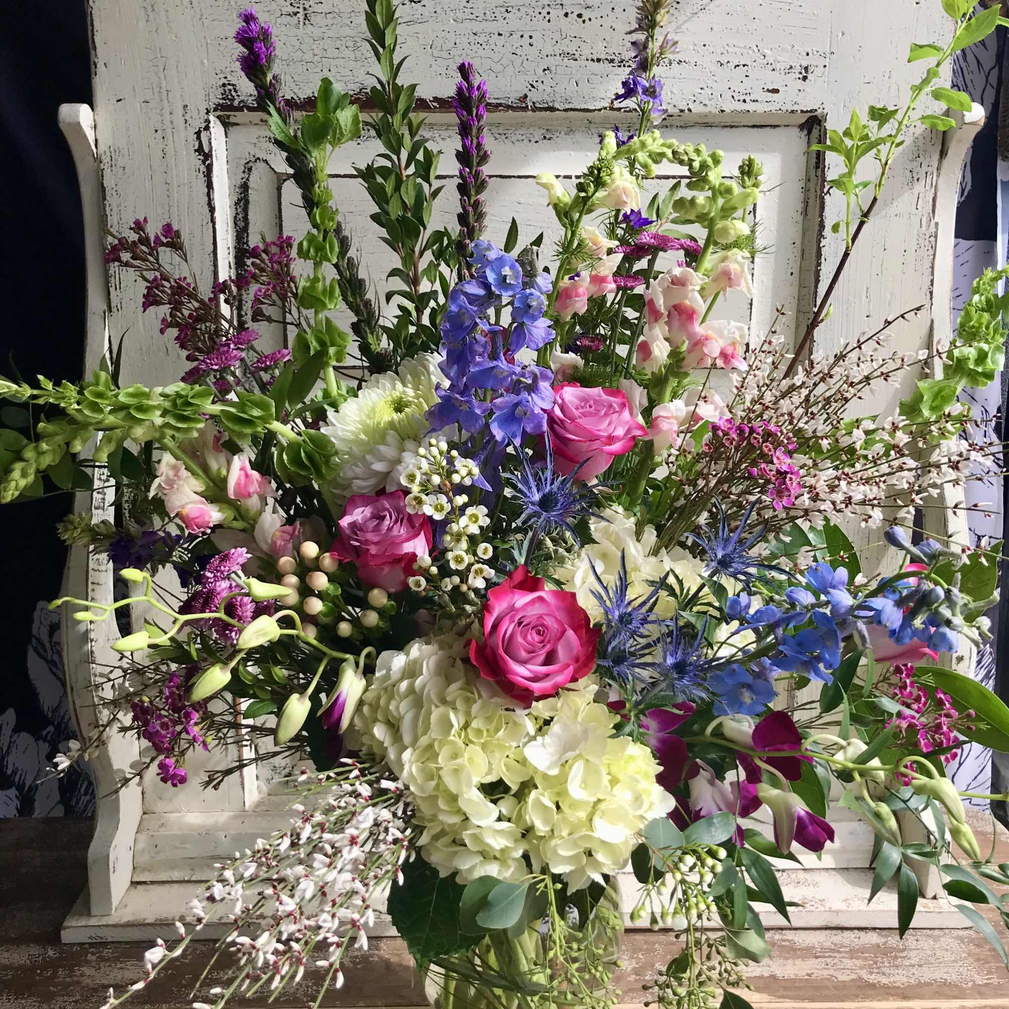 Mixed bouquet with pink roses, blue flowers, and white hydrangea in a glass vase