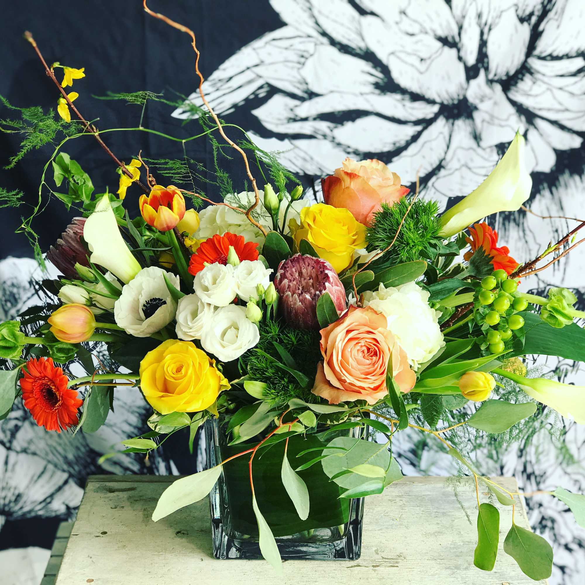 Mixed bouquet in a clear glass vase with roses and calla lilies
