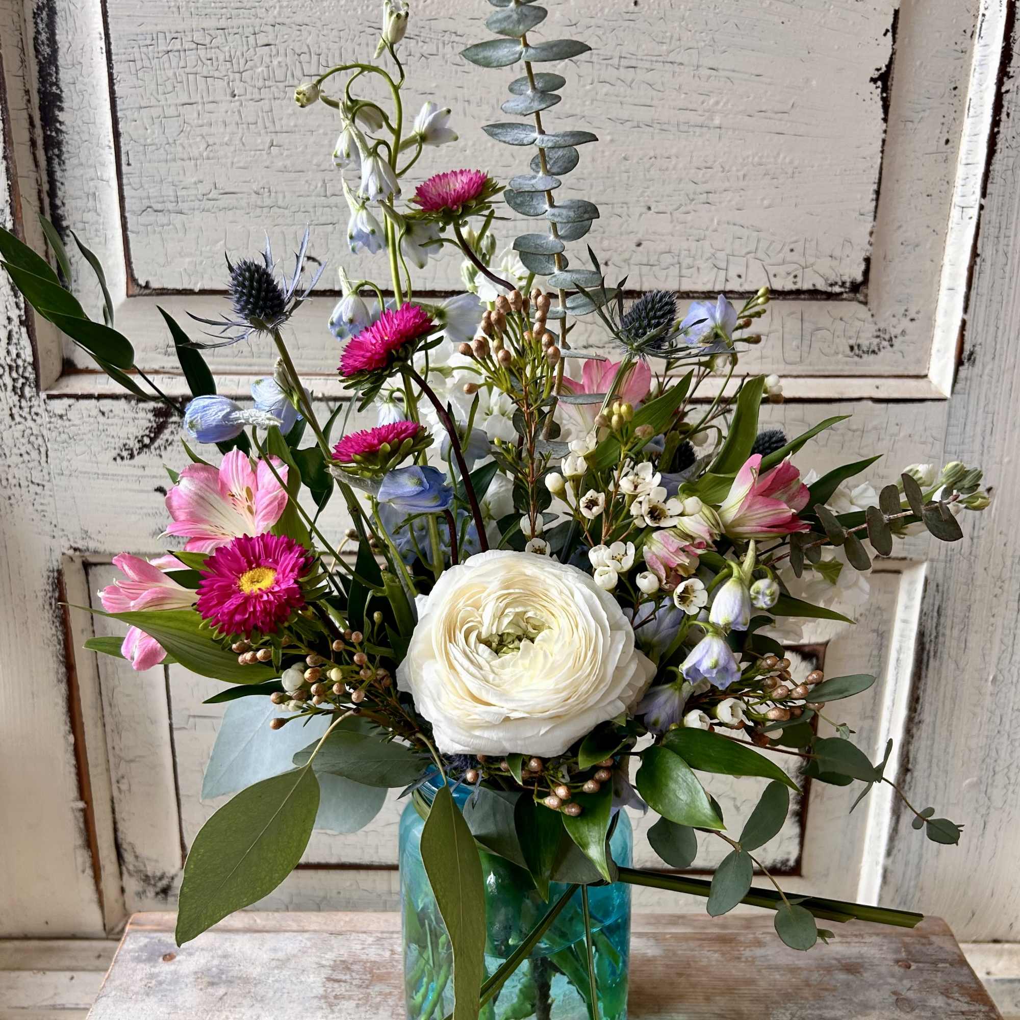 A small colored glass vase or jar holds a just right petite, photo 2 of 2