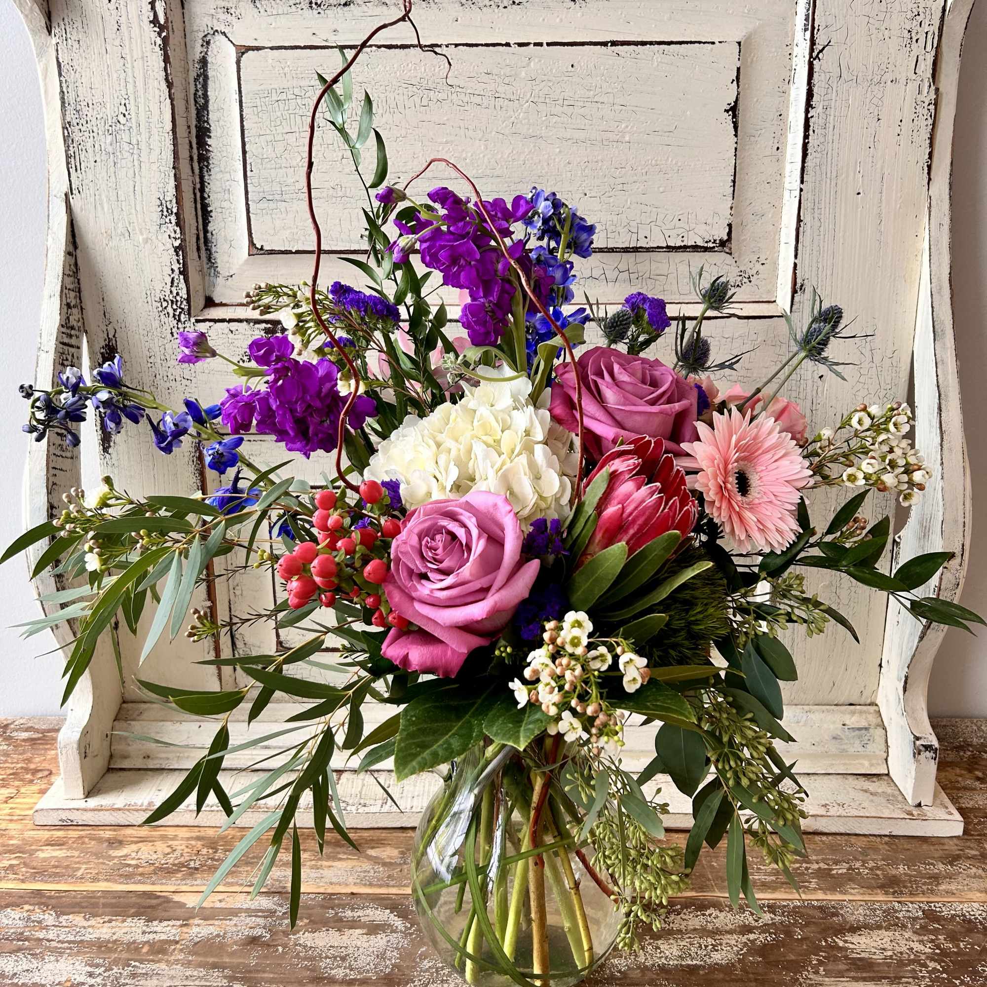Mixed bouquet in a clear glass vase with pink, purple, white, and blue flowers