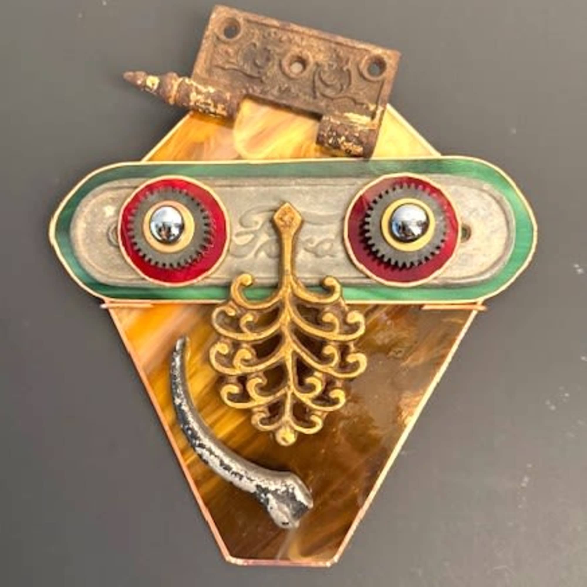 A whimsical steampunk-inspired wall sculpture that reads like a quirky mask -