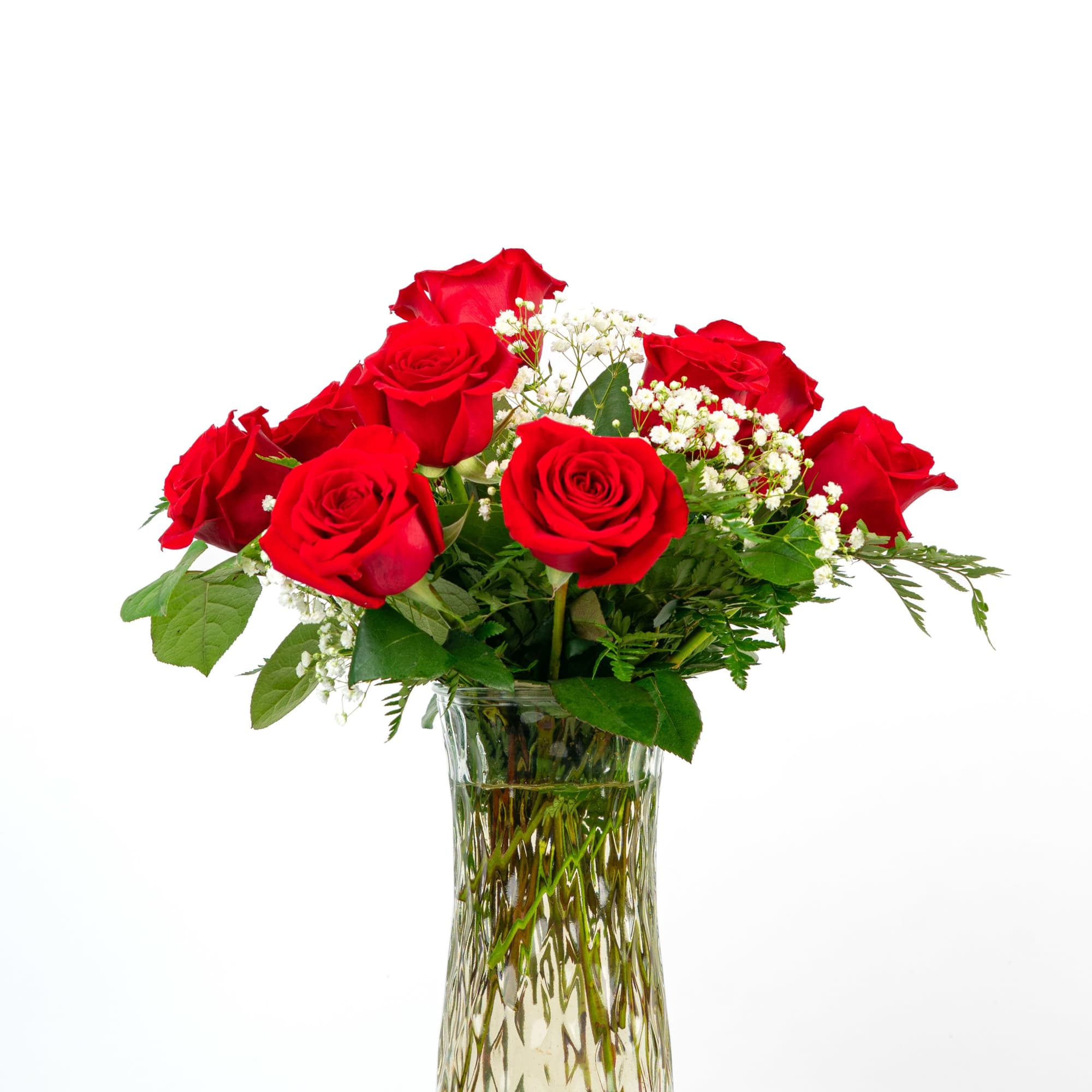Red roses arranged in a clear glass vase with white filler flowers