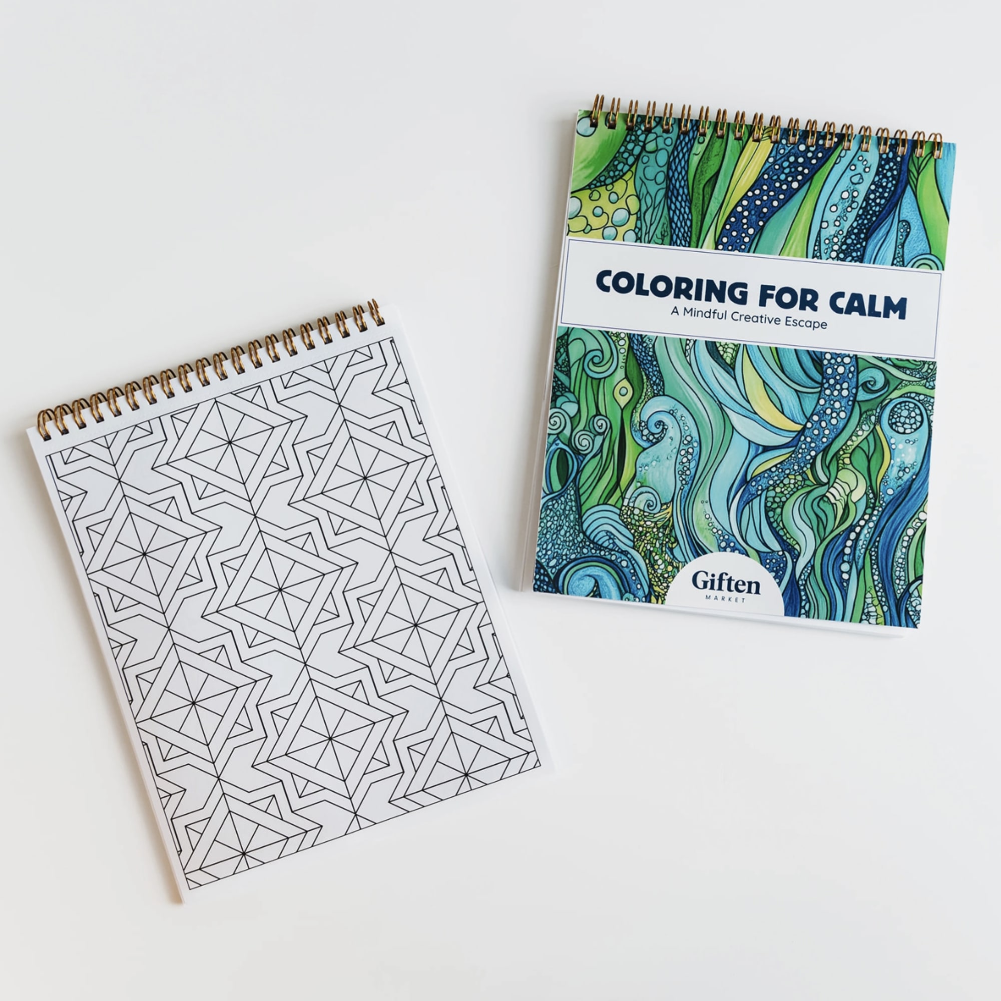 Two spiral-bound coloring books on a white surface, one patterned and one titled Coloring for Calm.