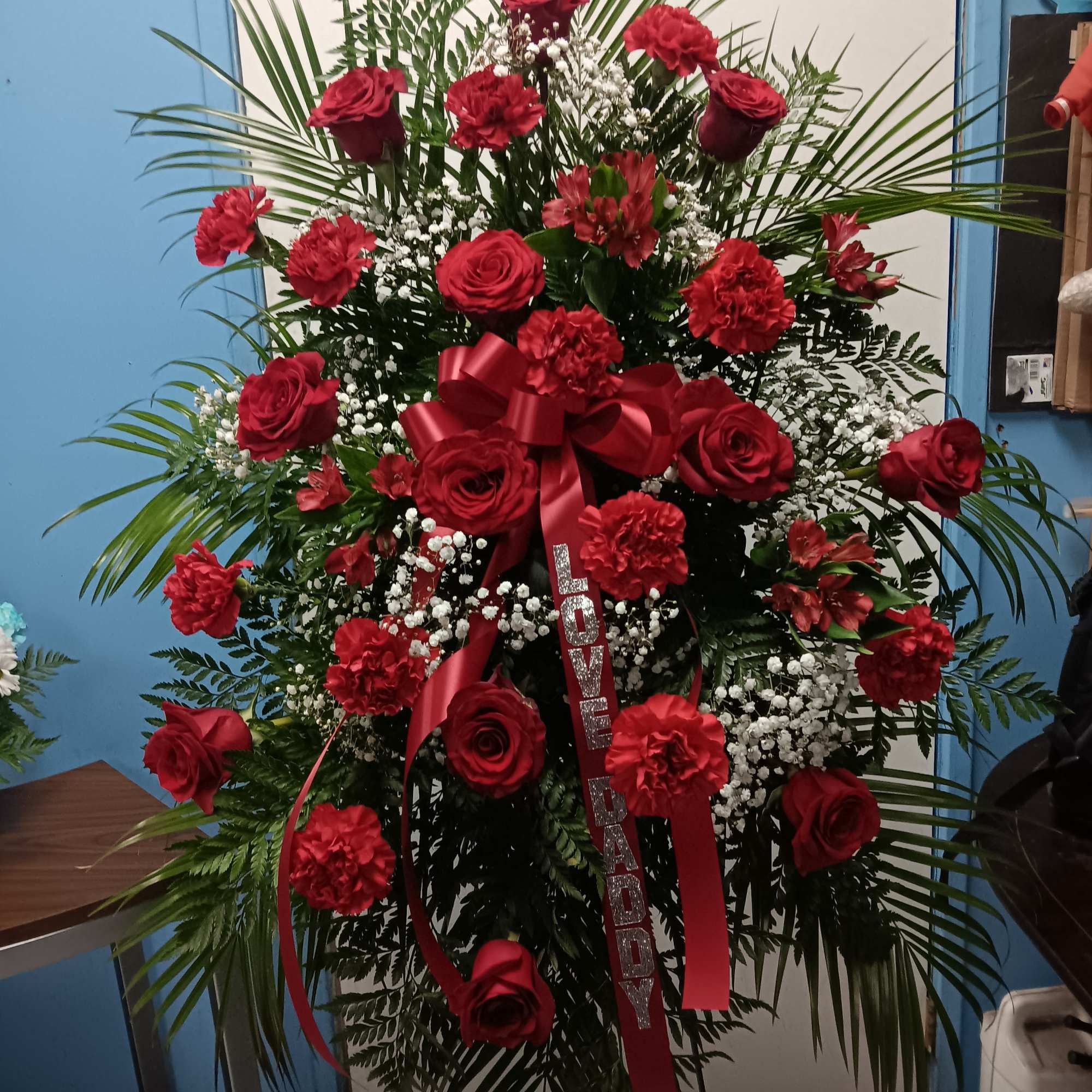 Large red floral standing spray with roses and carnations on an easel