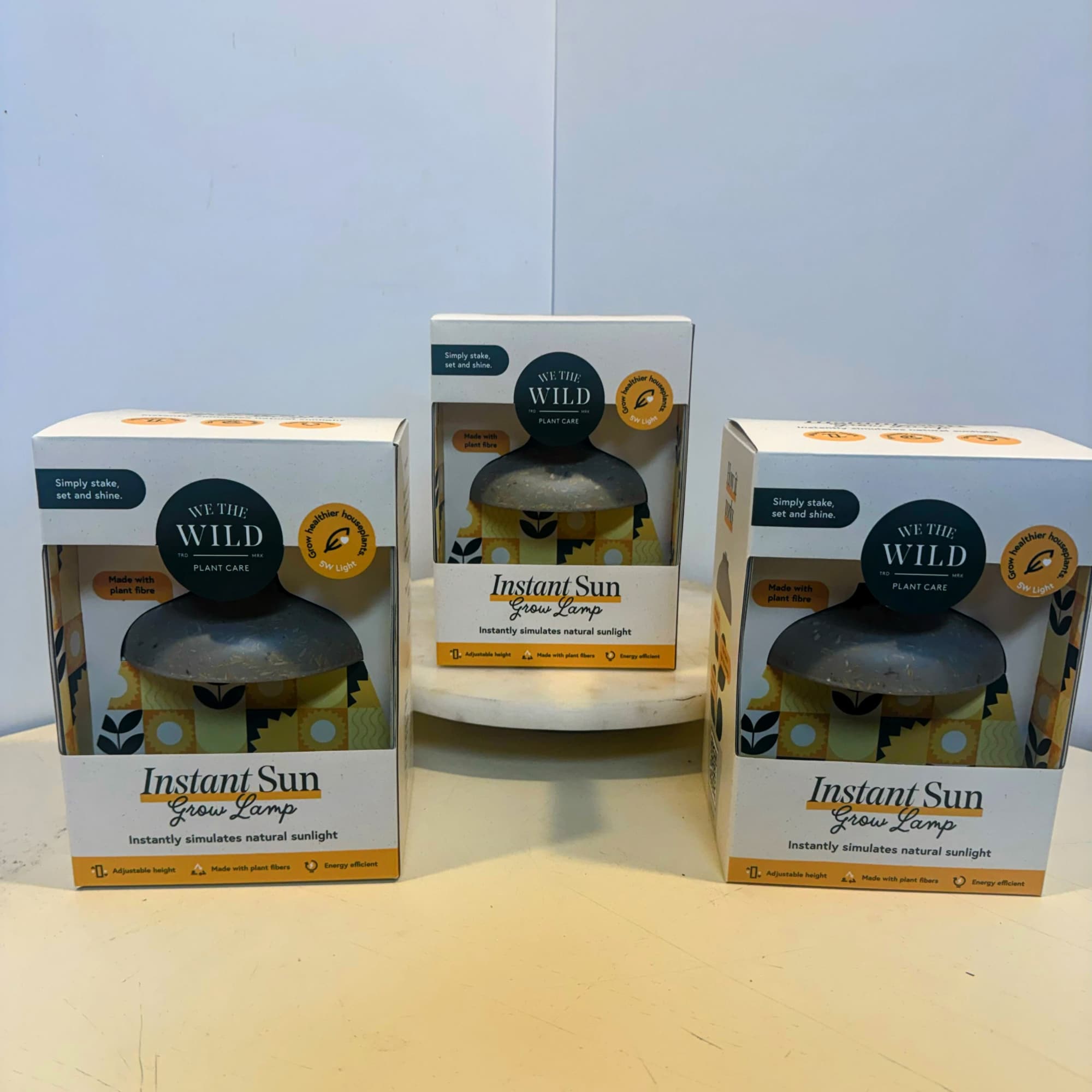 Three boxed grow lamps on a table.