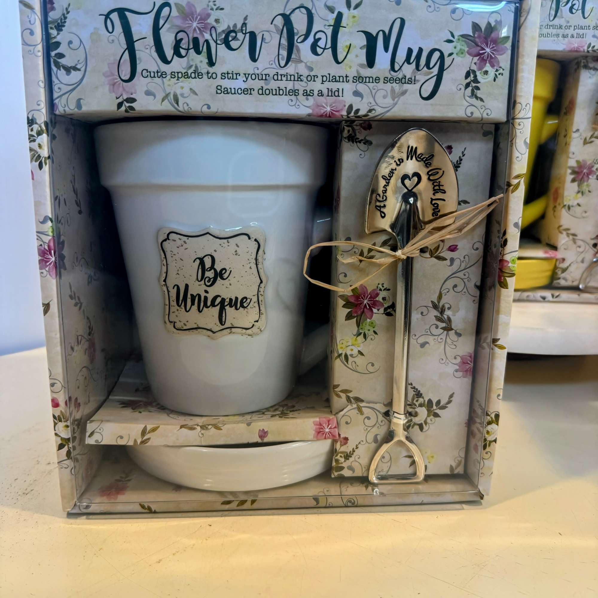 Gift set with a white flower pot, saucer, and metal spade in floral packaging