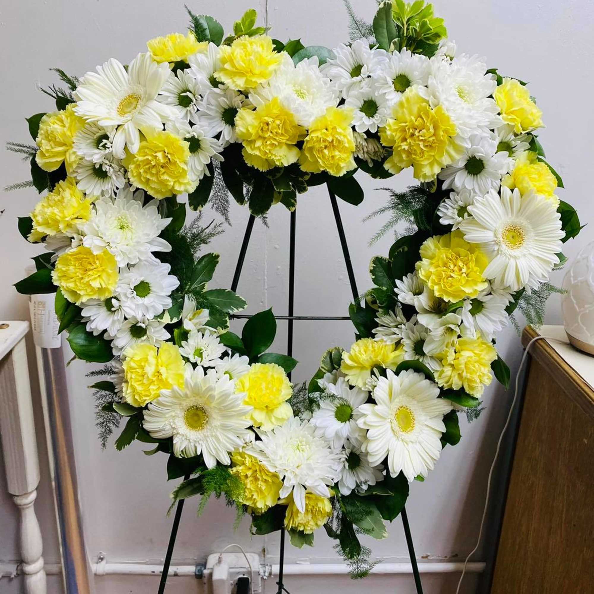 Heart-shaped floral wreath with white daisies and yellow carnations