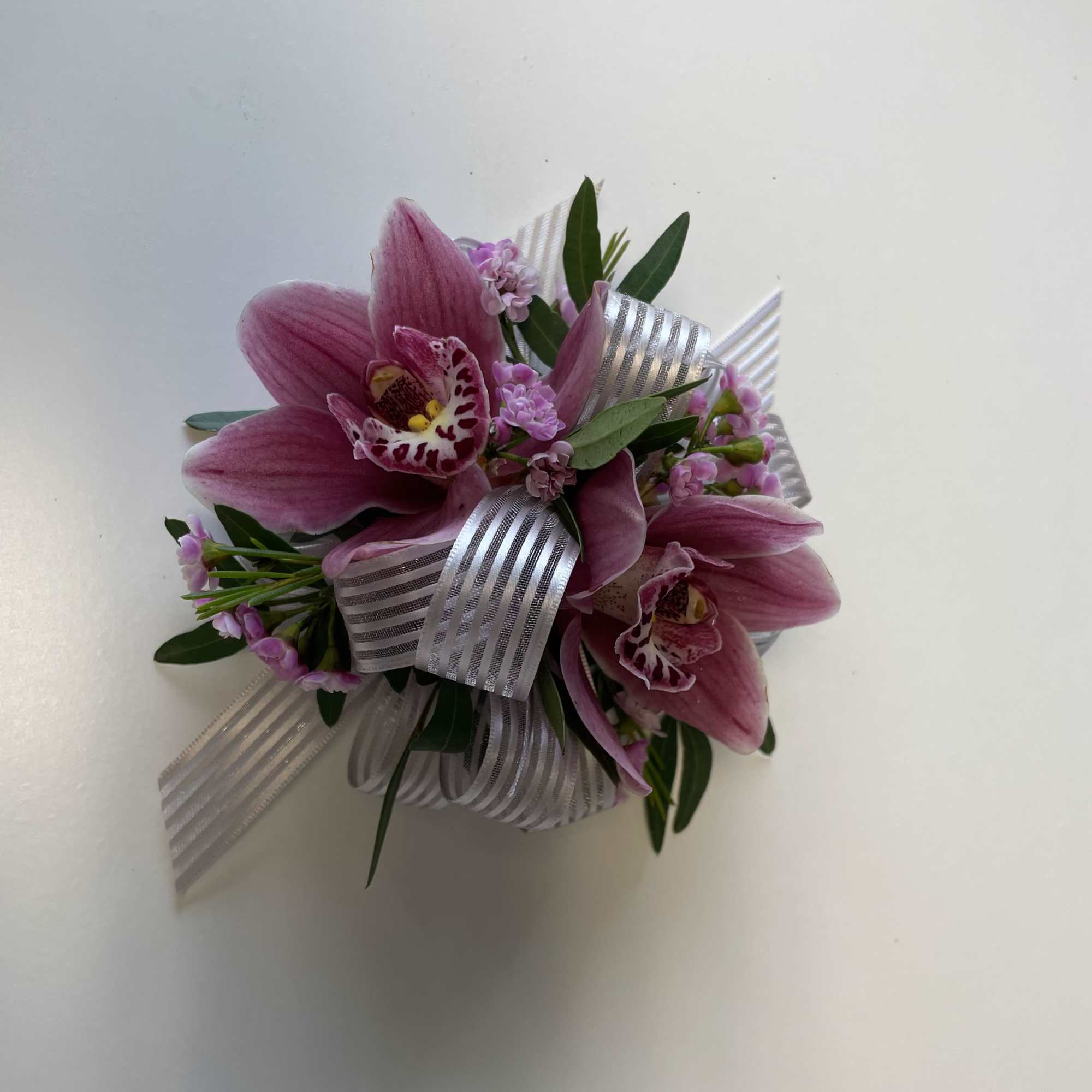Pink orchid corsage with silver ribbon and greenery