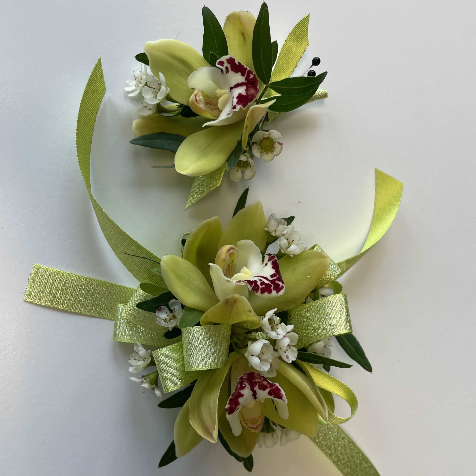 Two orchid corsages with lime ribbon and white accents