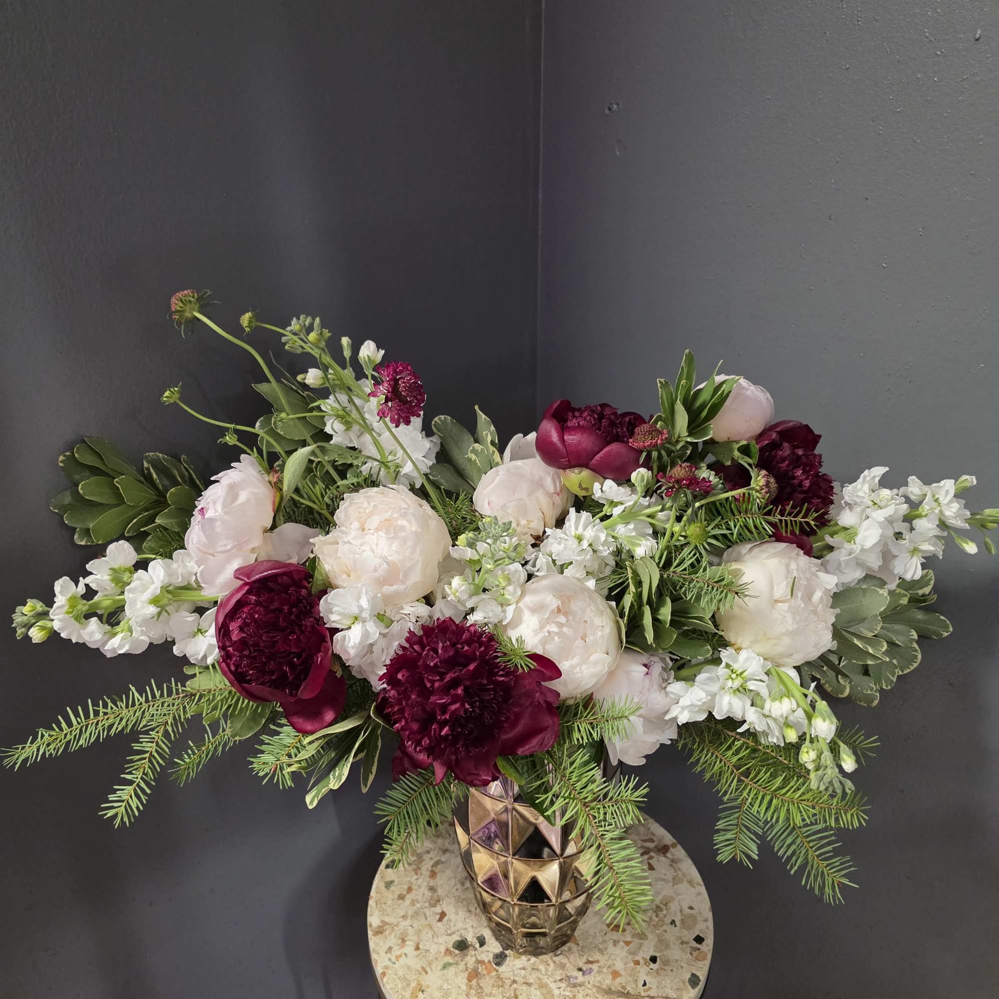 Low floral arrangement with white and deep burgundy blooms in a gold vase