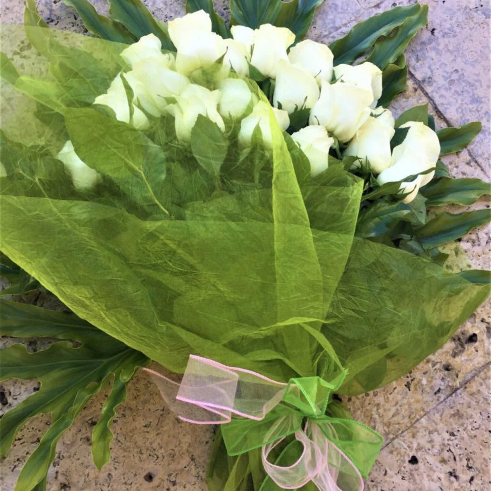 Bouquet of white roses wrapped in bright green tissue with a pink and green ribbon.