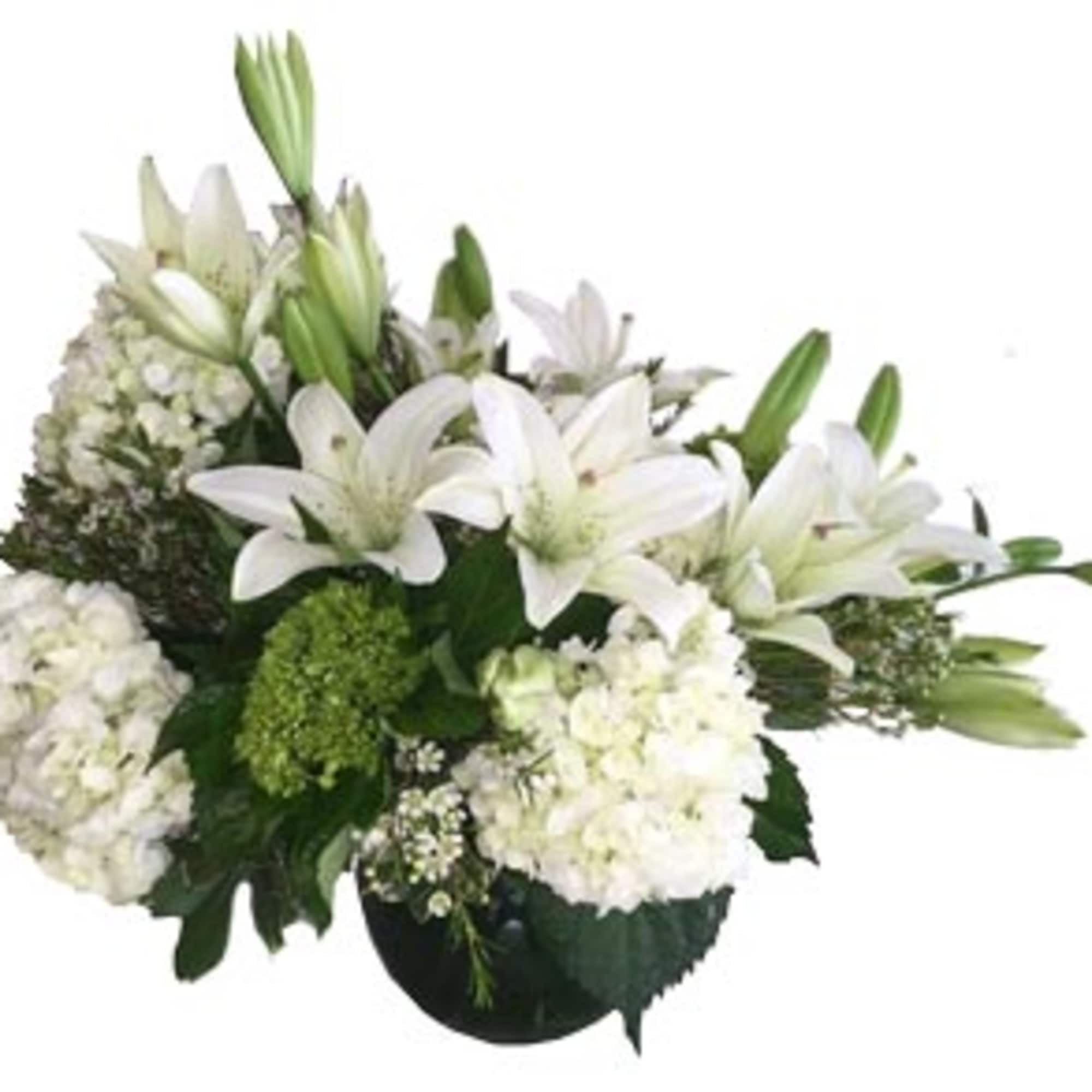 Low arrangement of white lilies and white hydrangeas in a round dark glass vase