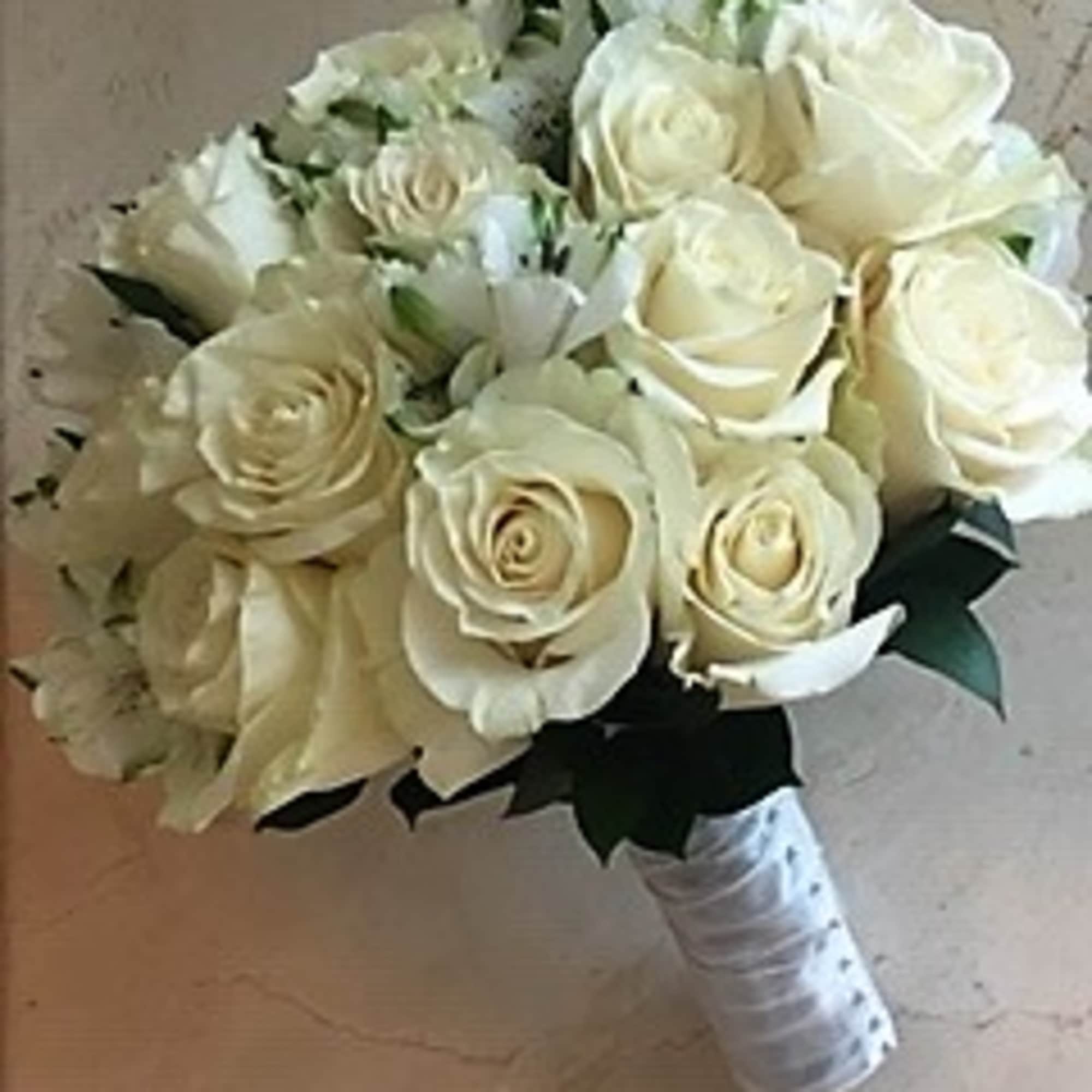 Hand-tied bouquet of ivory roses with small white blooms and a wrapped handle