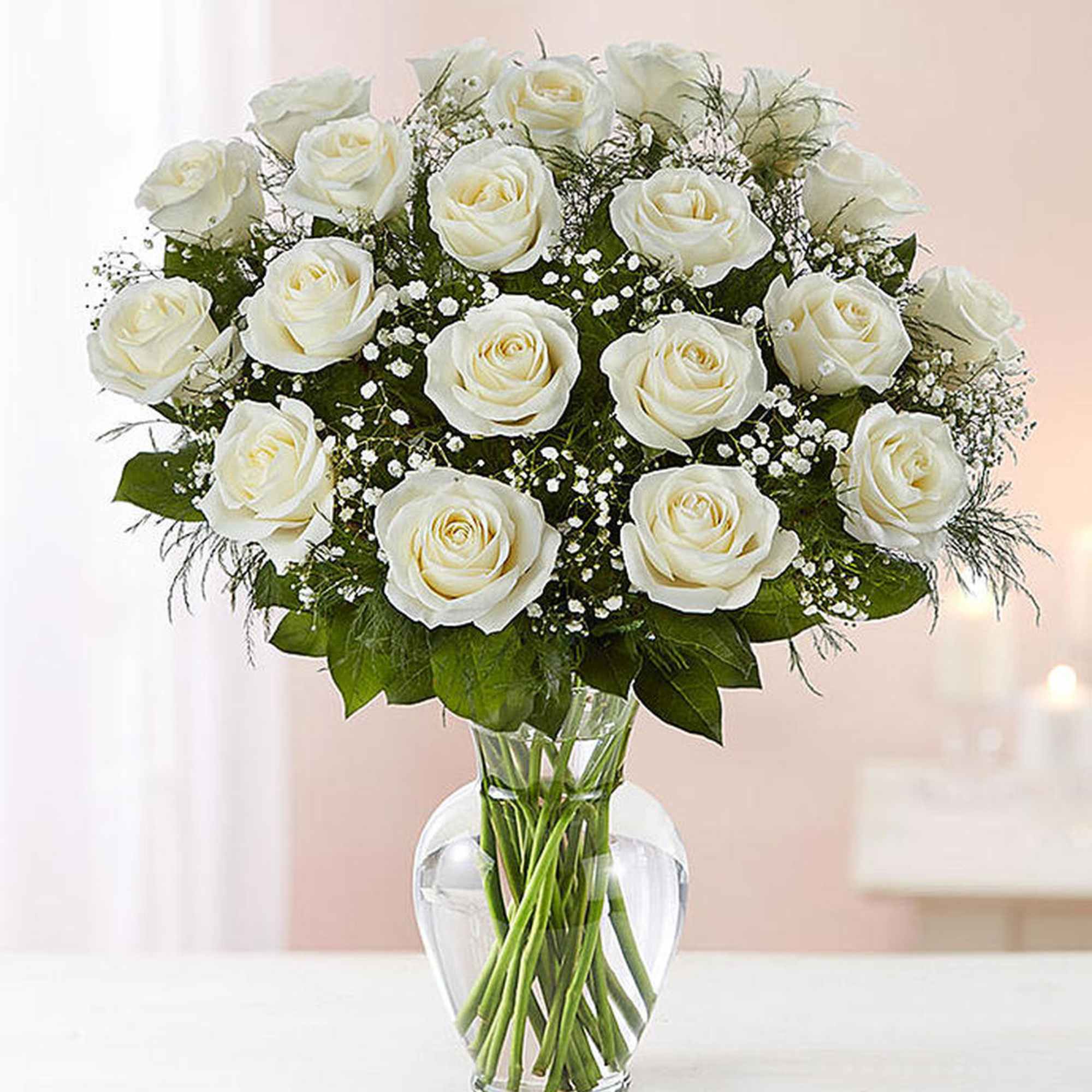 Arrangement of white roses with filler flowers in a clear glass vase