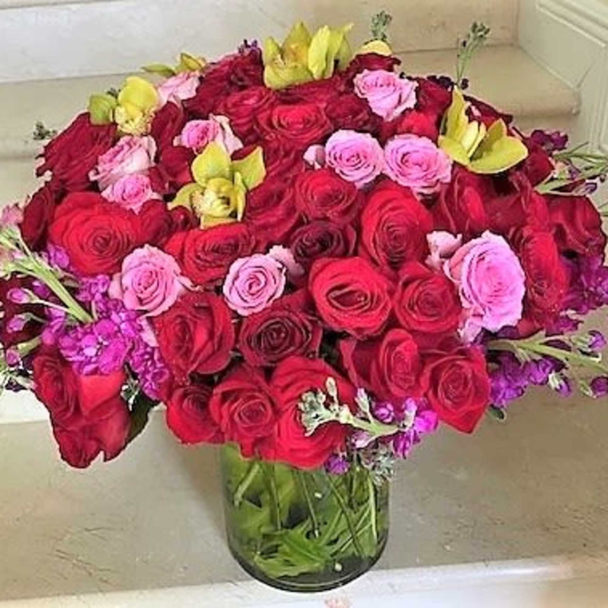 Red and Pink Roses with Cymbidium Orchids and Fragrant Stock arranged round