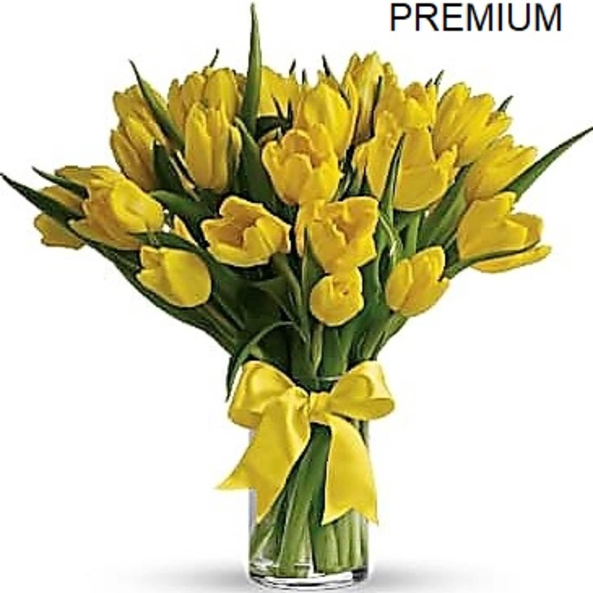 Arrangement of yellow tulips in a clear glass vase tied with a yellow ribbon bow