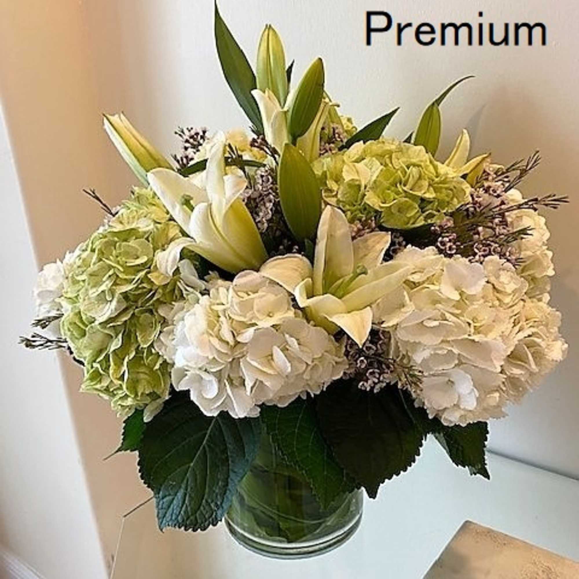 Round arrangement of white lilies and hydrangeas in a clear glass vase