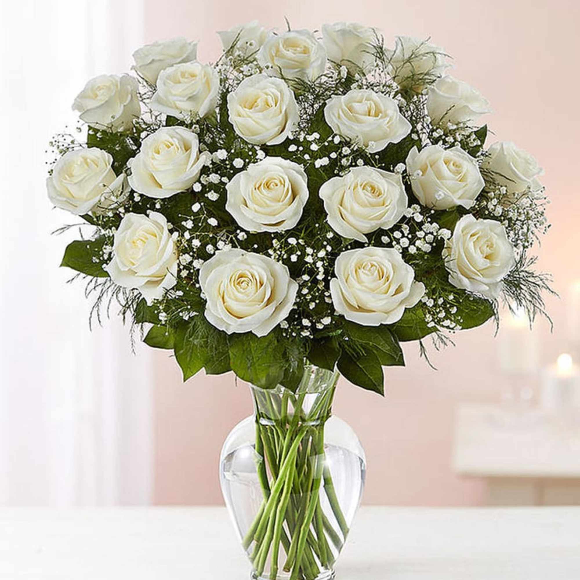 Arrangement of white roses with baby's breath in a clear glass vase