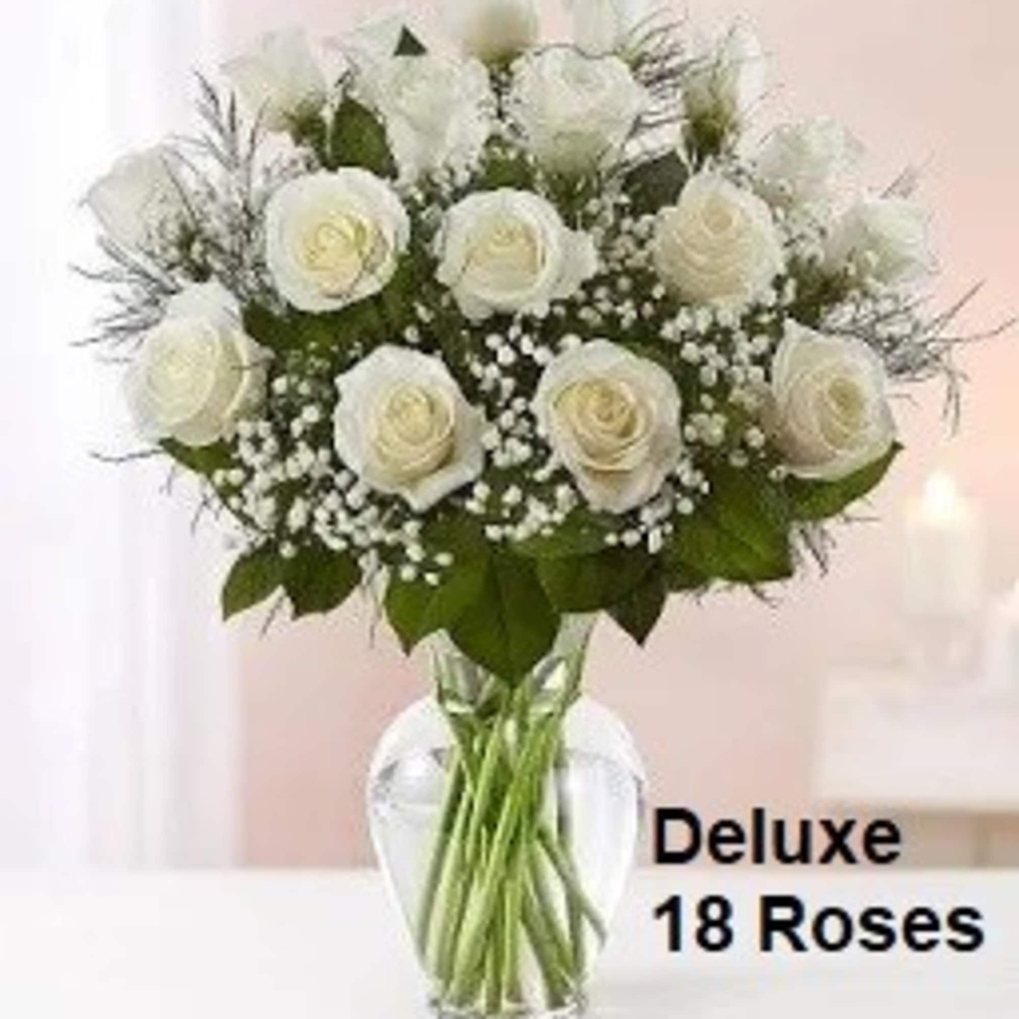 Arrangement of 18 white roses with baby's breath in a clear glass vase