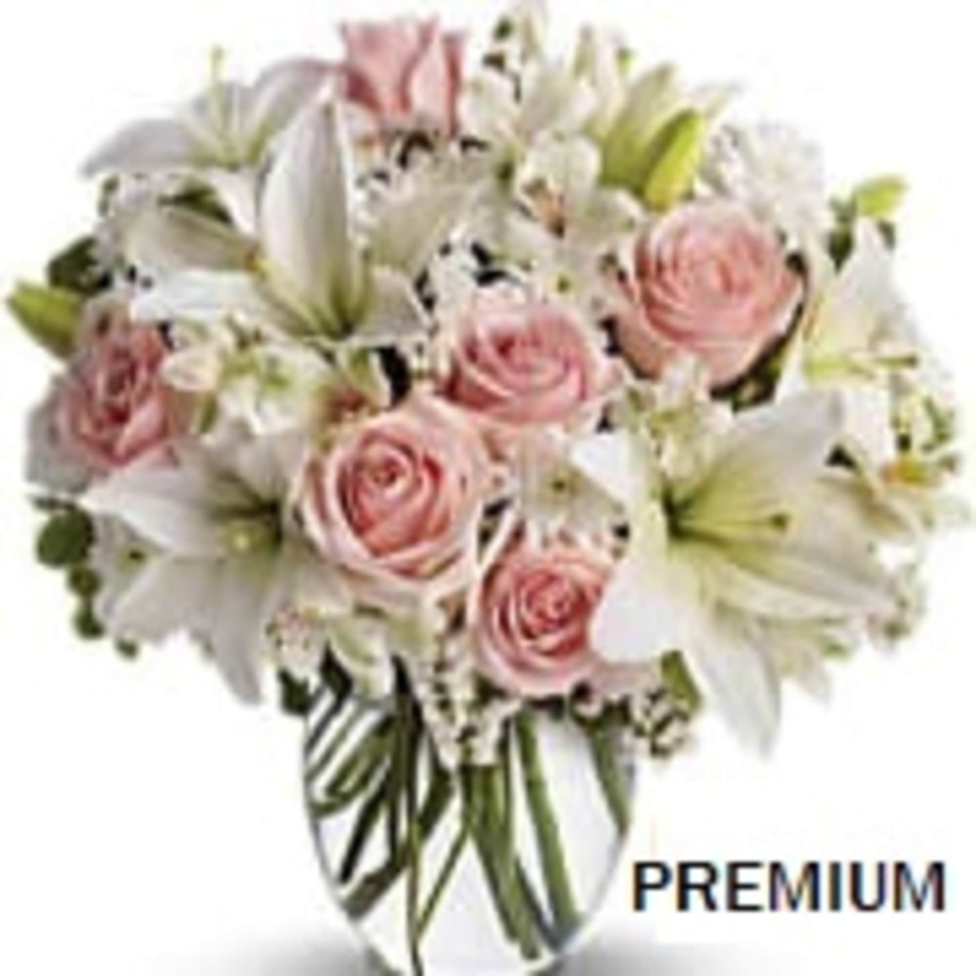 Round bouquet of pale pink roses and white lilies in a clear glass vase