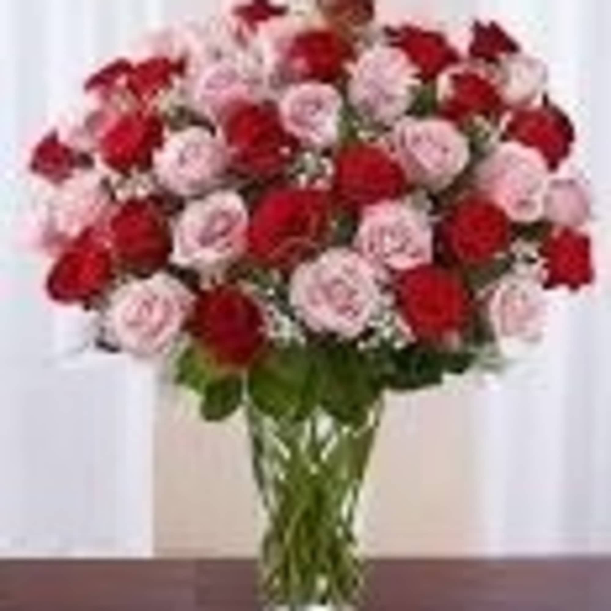 Large bouquet of red and pink roses arranged in a clear glass vase