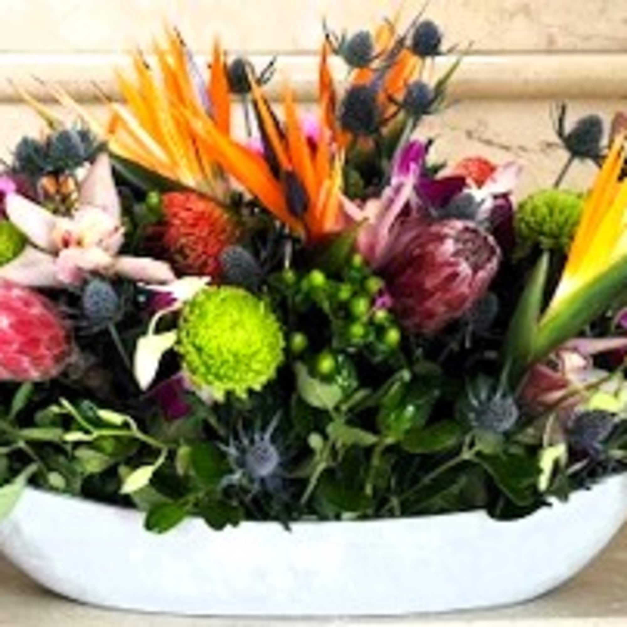 Low floral centerpiece with pink and purple blooms in a white bowl vase