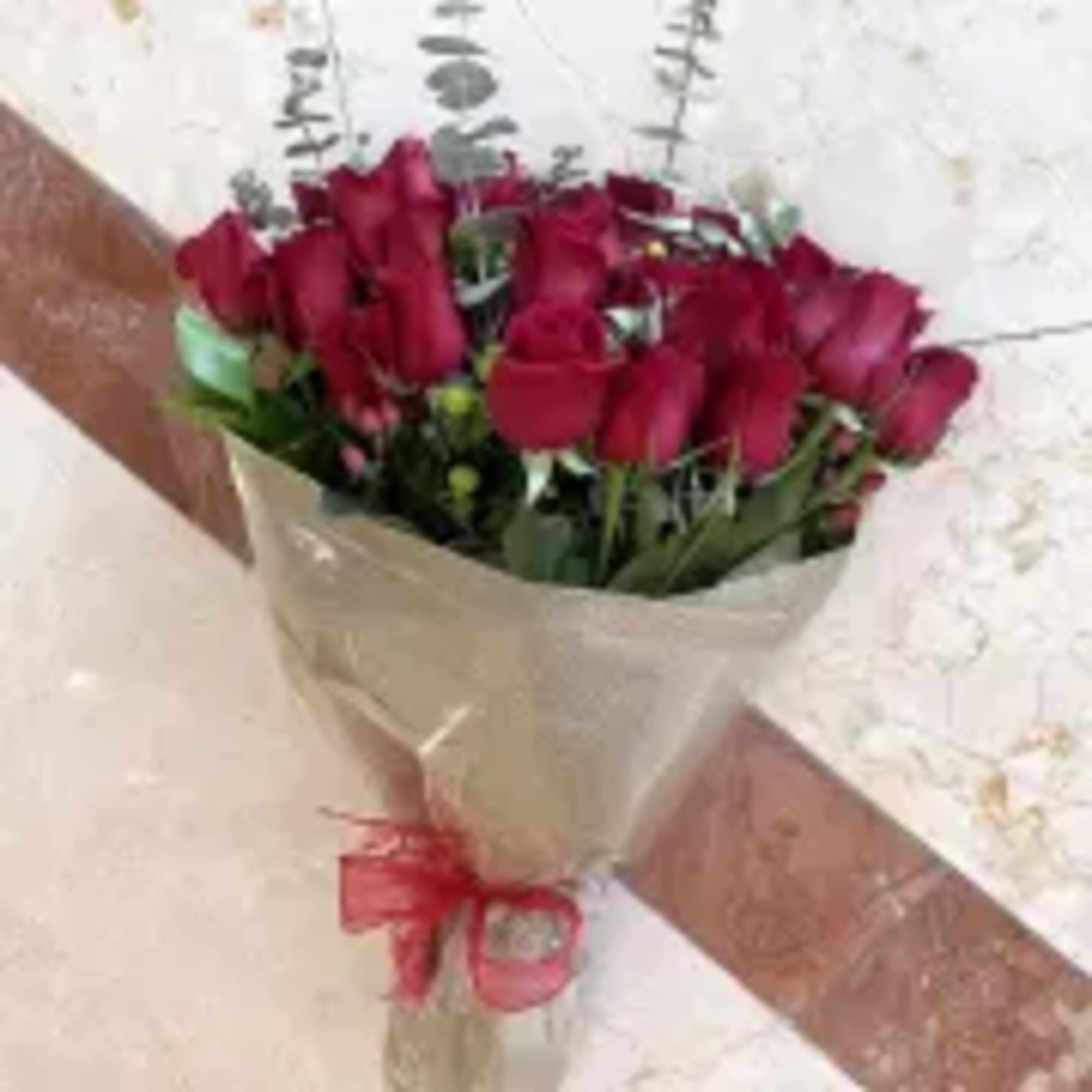 Bouquet of red roses wrapped in burlap-style paper with a red ribbon bow