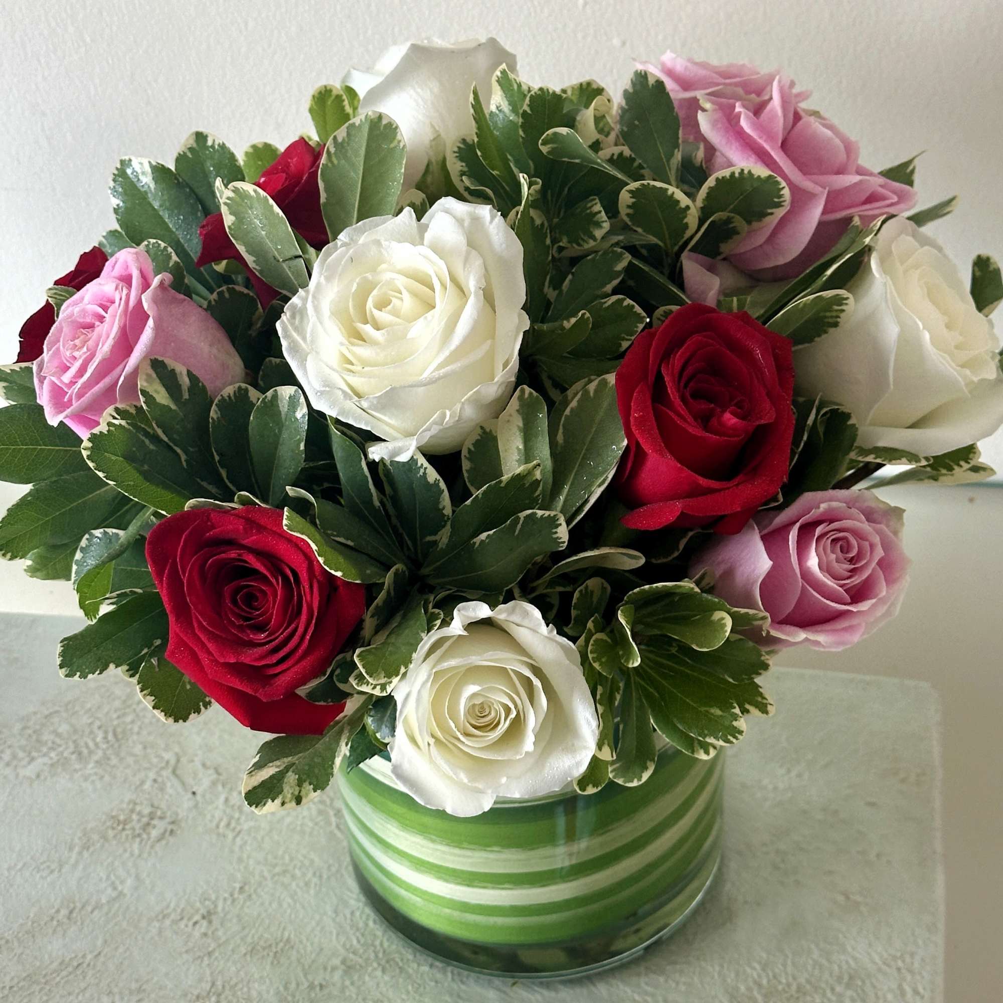 Bouquet of red, white, and pink roses in a striped glass vase