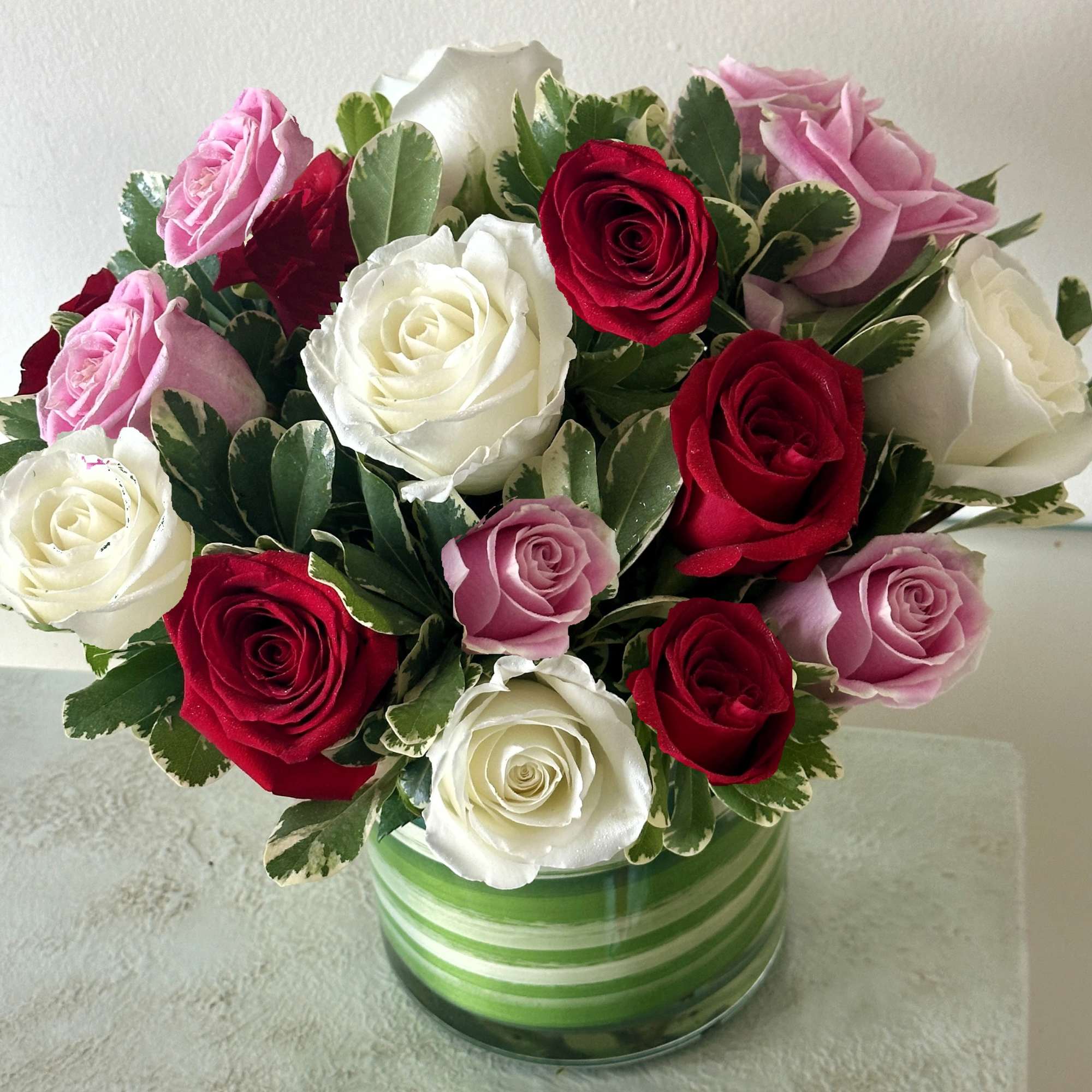 Bouquet of red, white, and pink roses in a striped glass vase