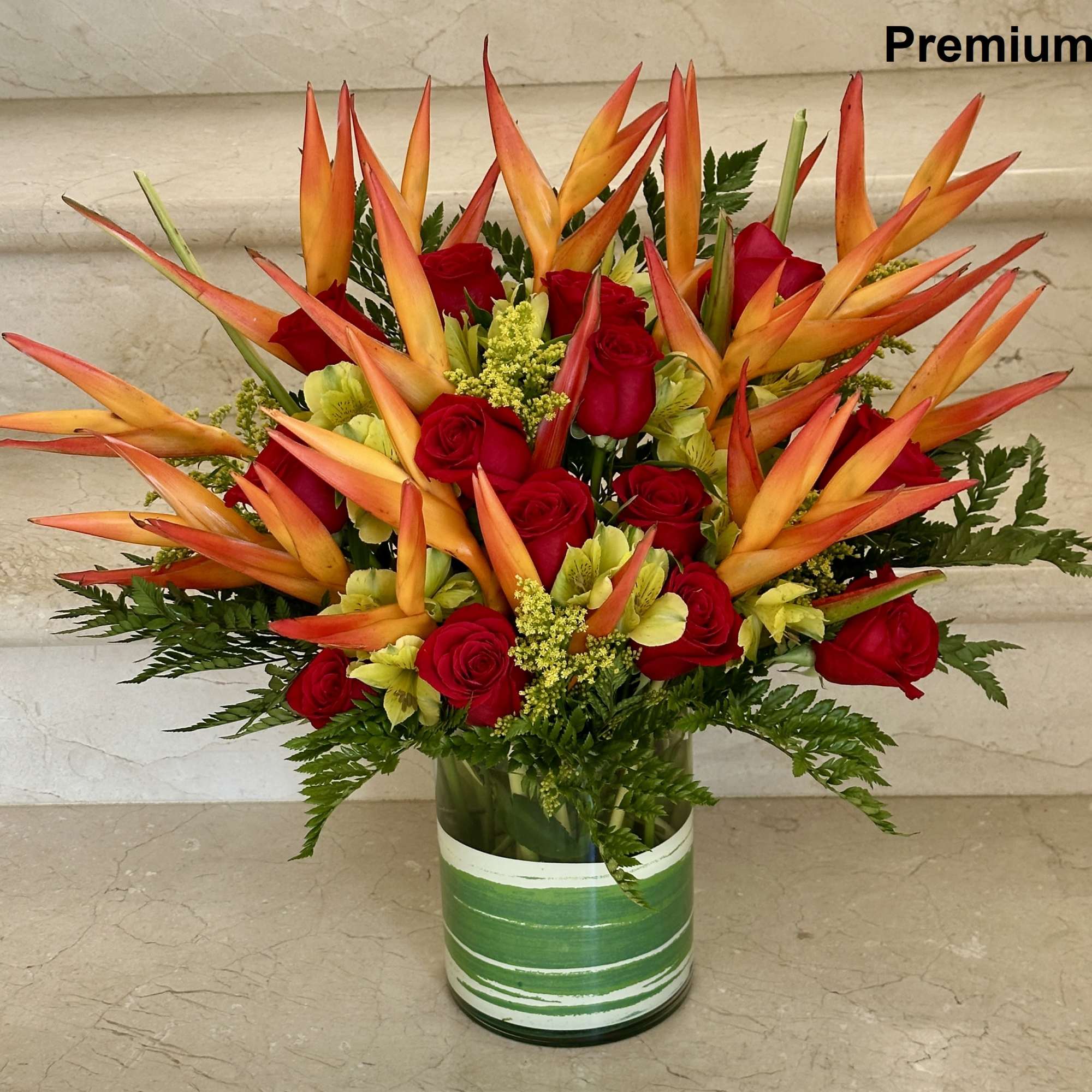 Red roses and orange tropical flowers in a glass vase