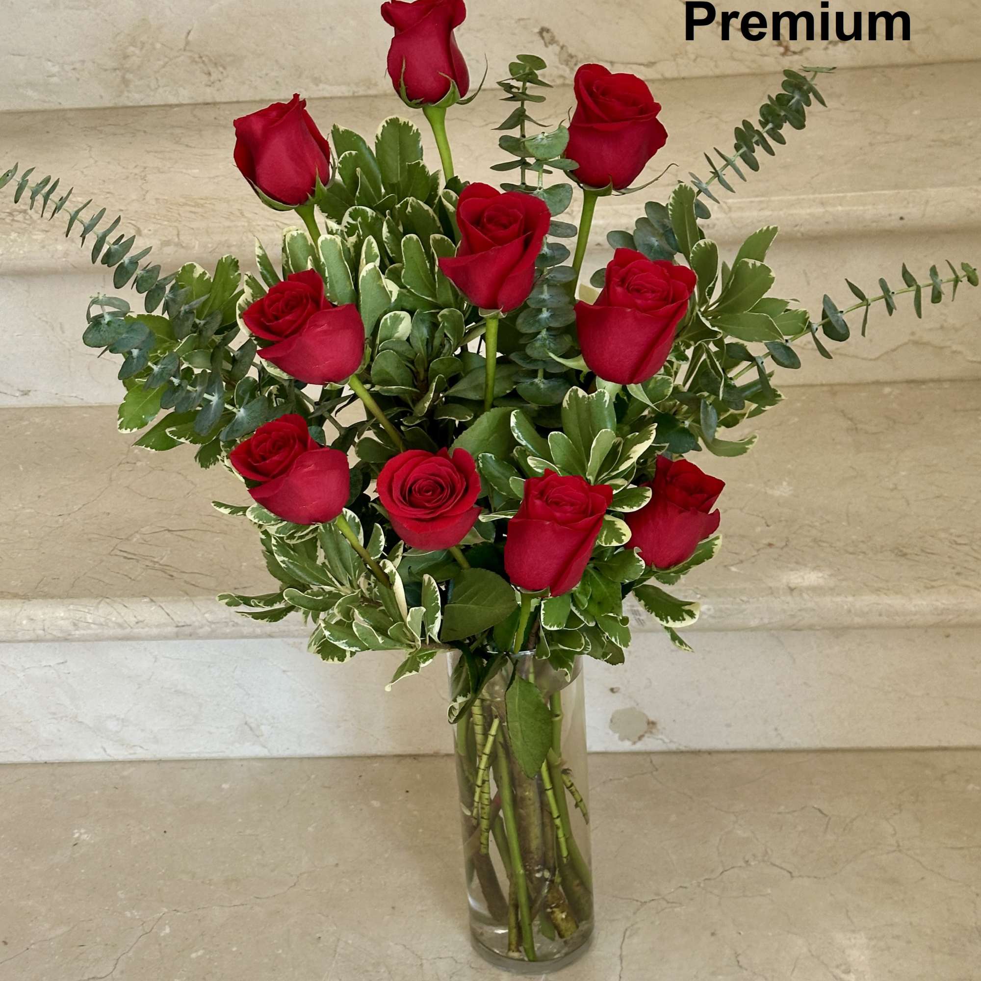 Tall arrangement of long-stem red roses in a clear glass vase