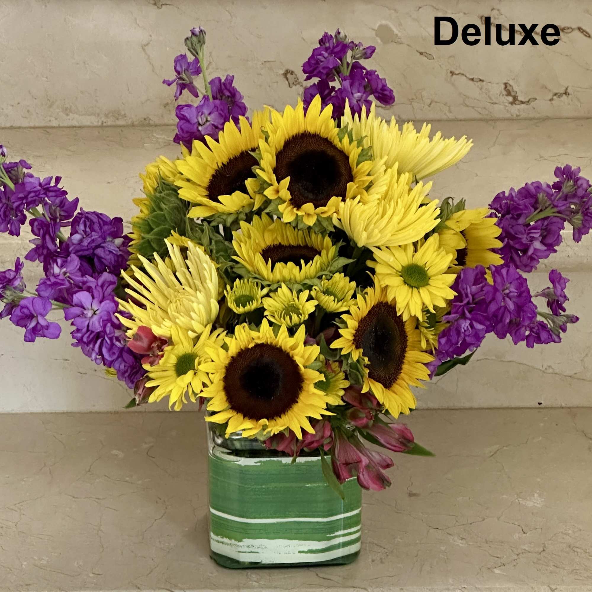 Sunflower and purple flower arrangement in a green striped vase
