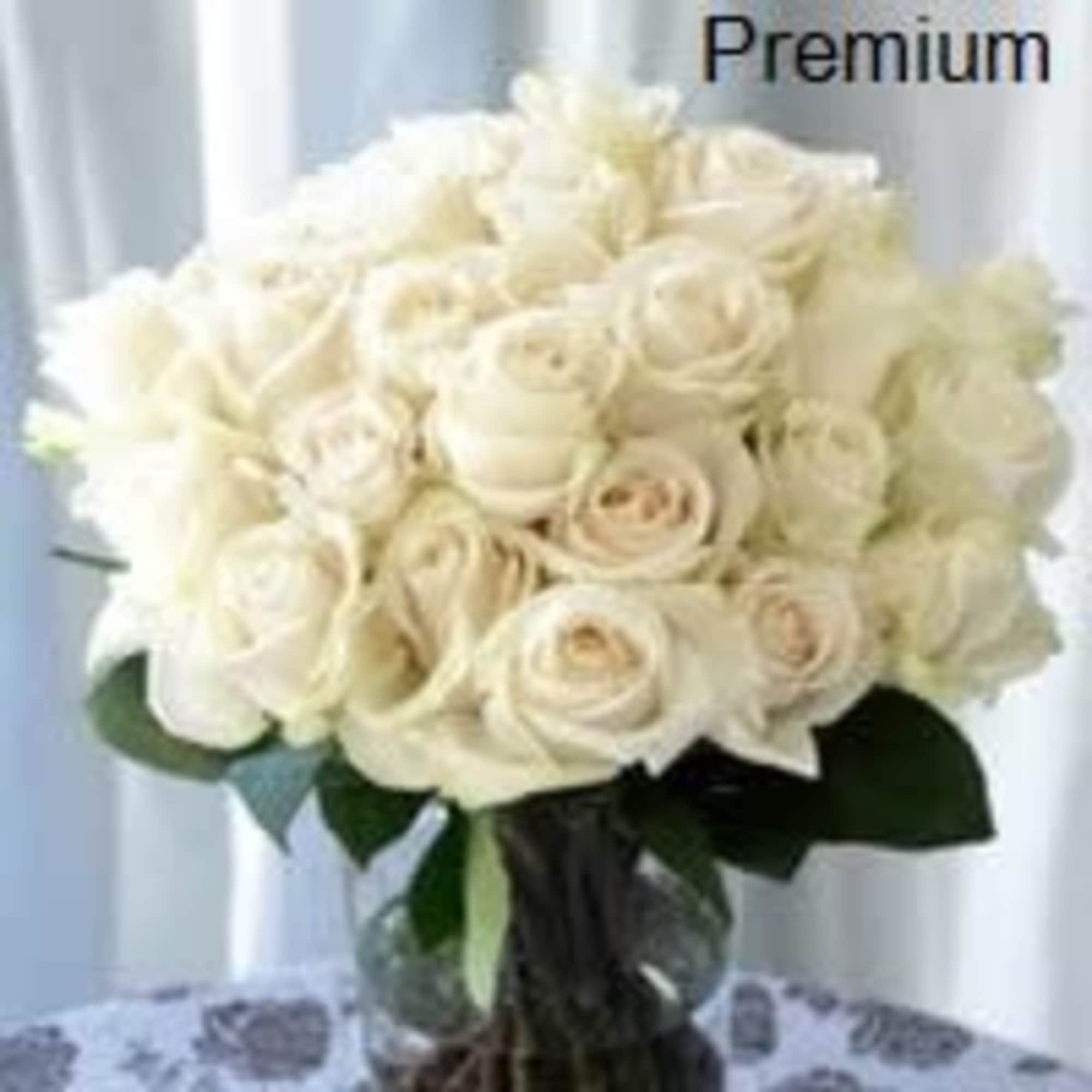 Large bouquet of white roses arranged in a clear glass vase on a table