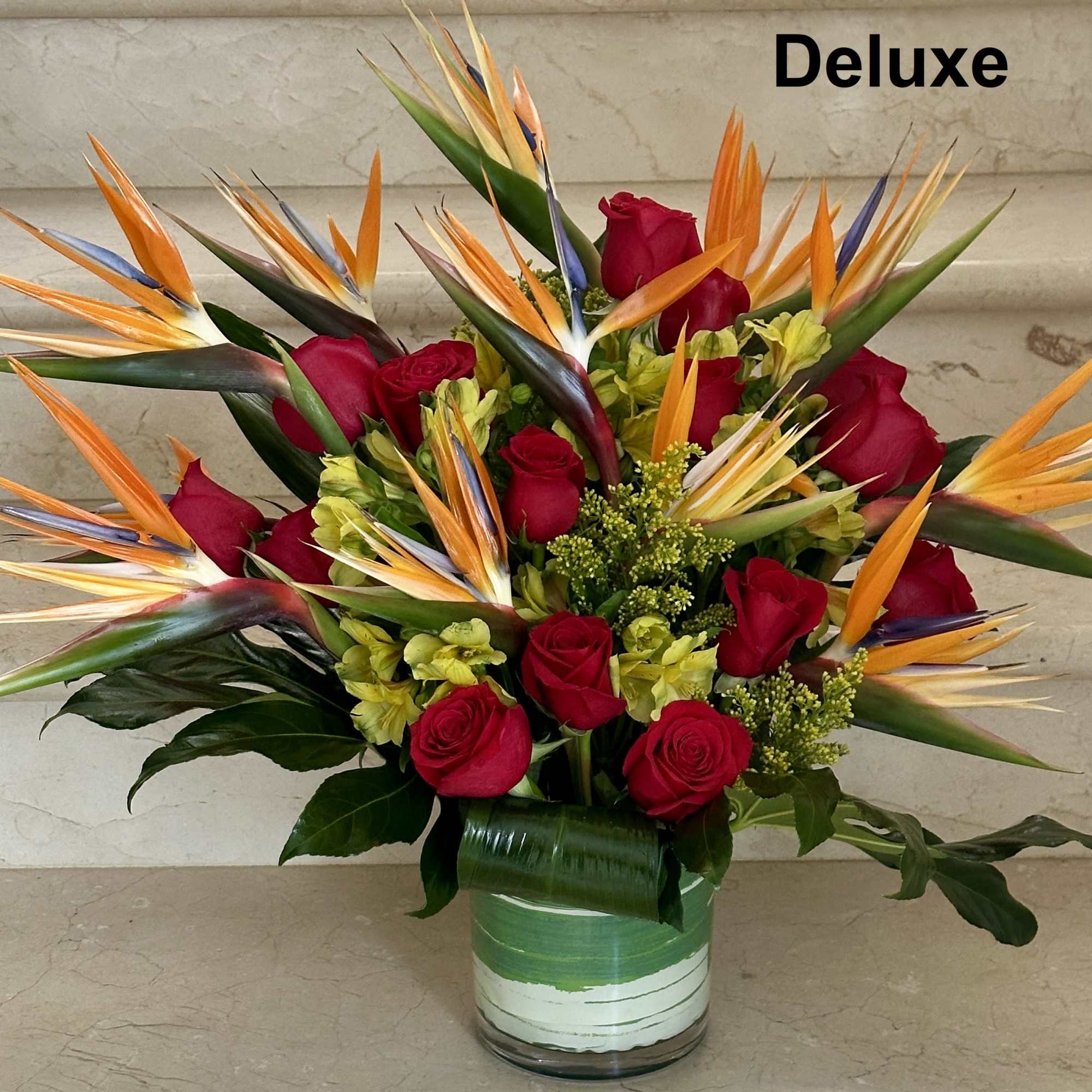 Bouquet of red roses and bird of paradise in a glass vase