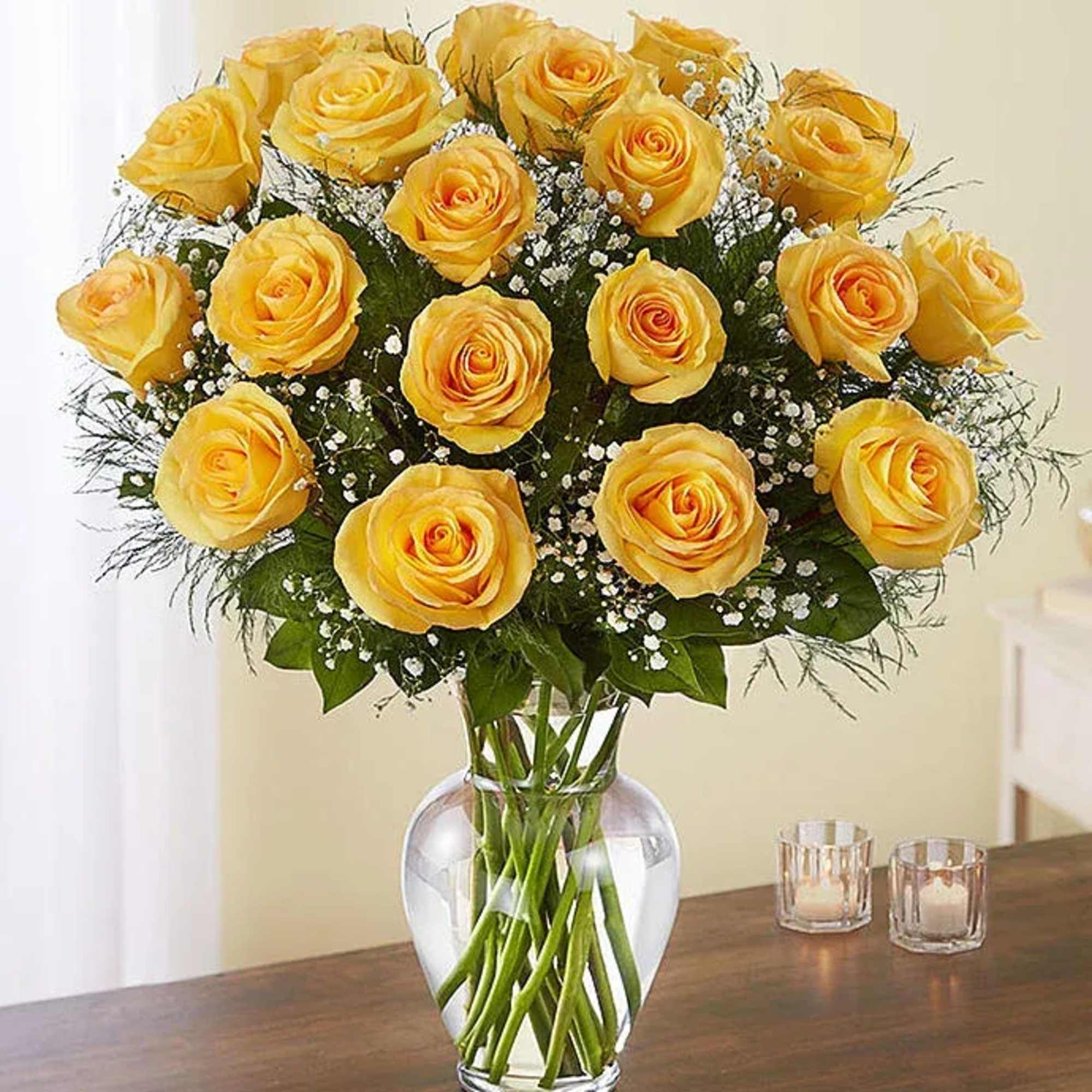 Yellow roses arranged in a clear glass vase with baby's breath