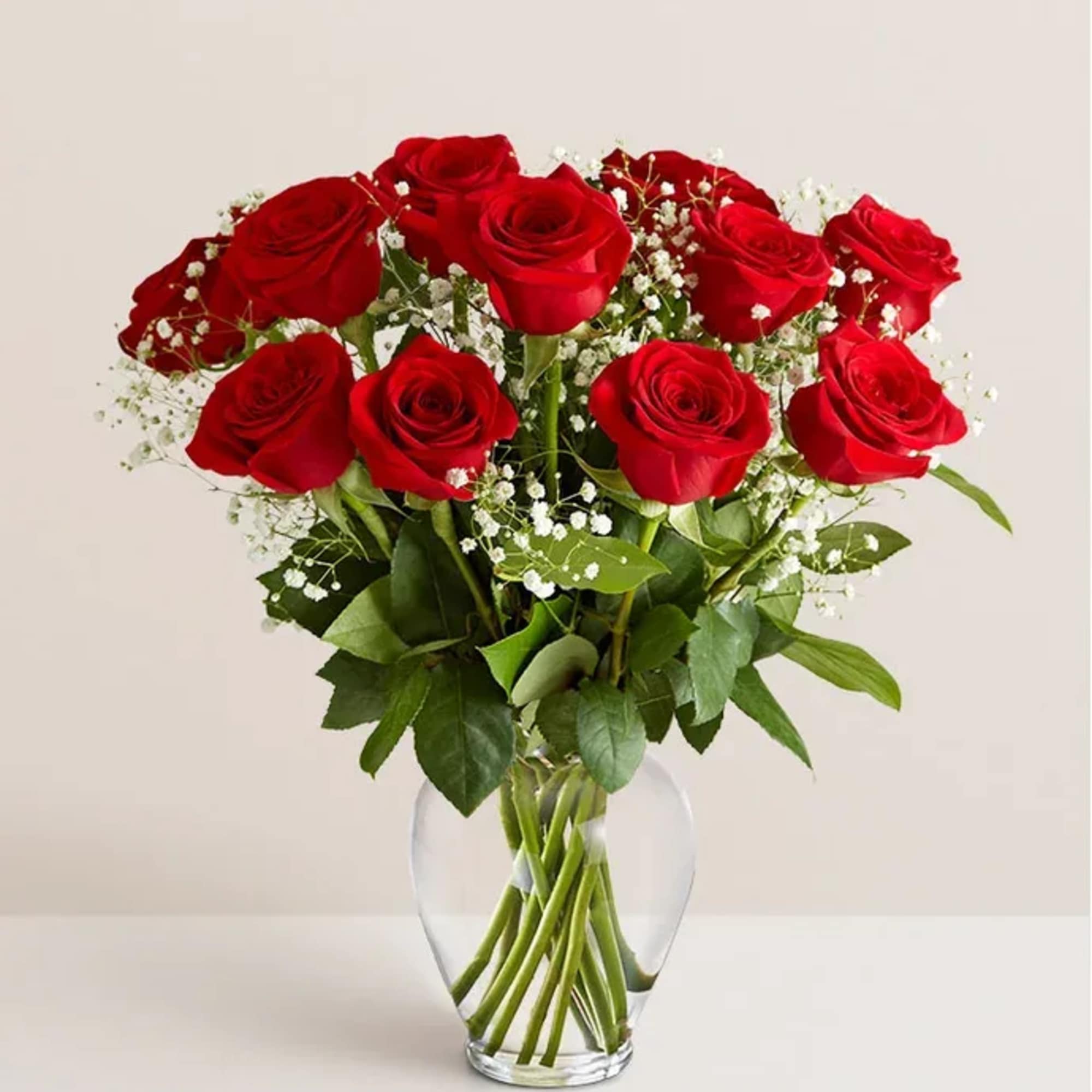 Red roses arranged in a clear glass vase with white baby's breath