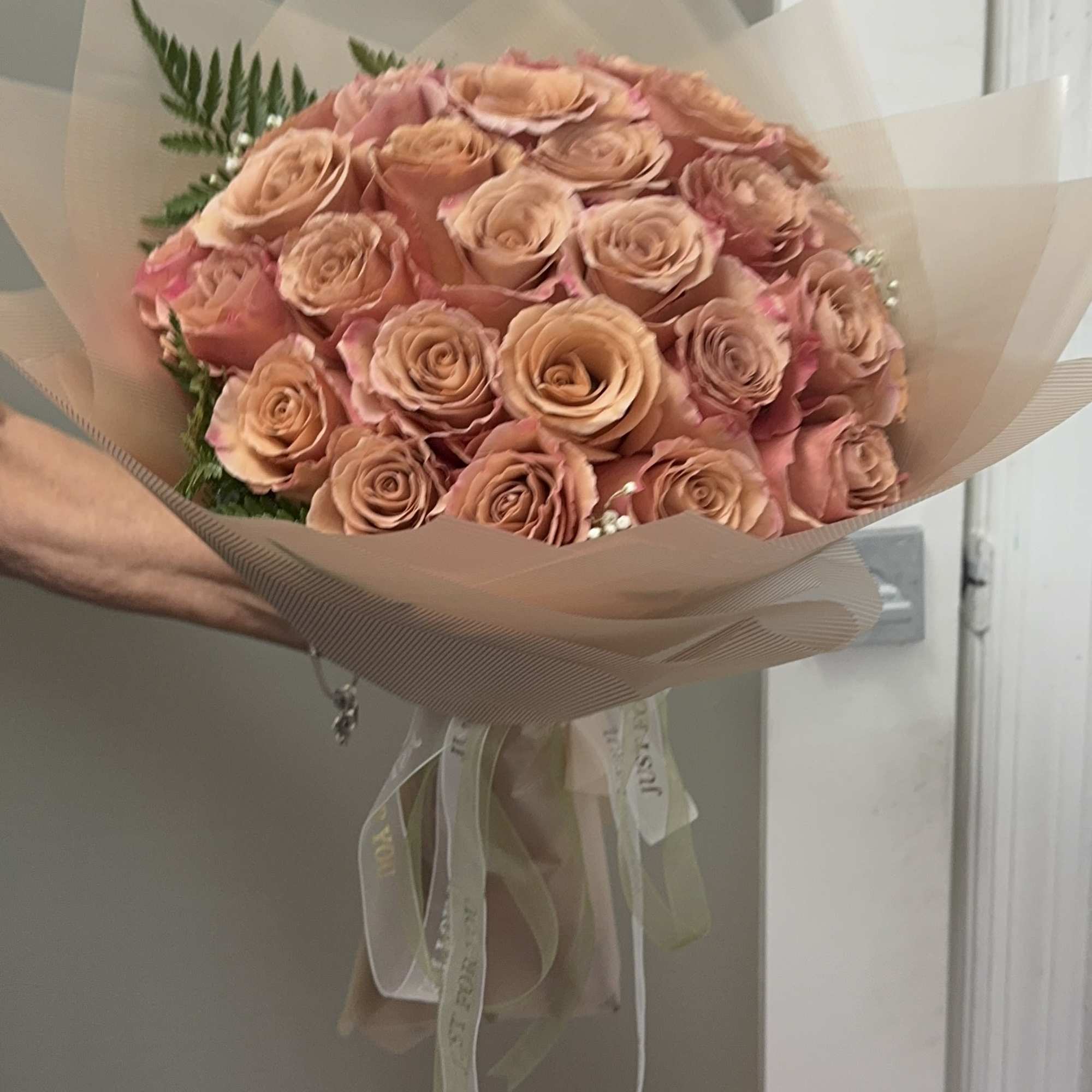 Bouquet of peach roses wrapped in translucent paper