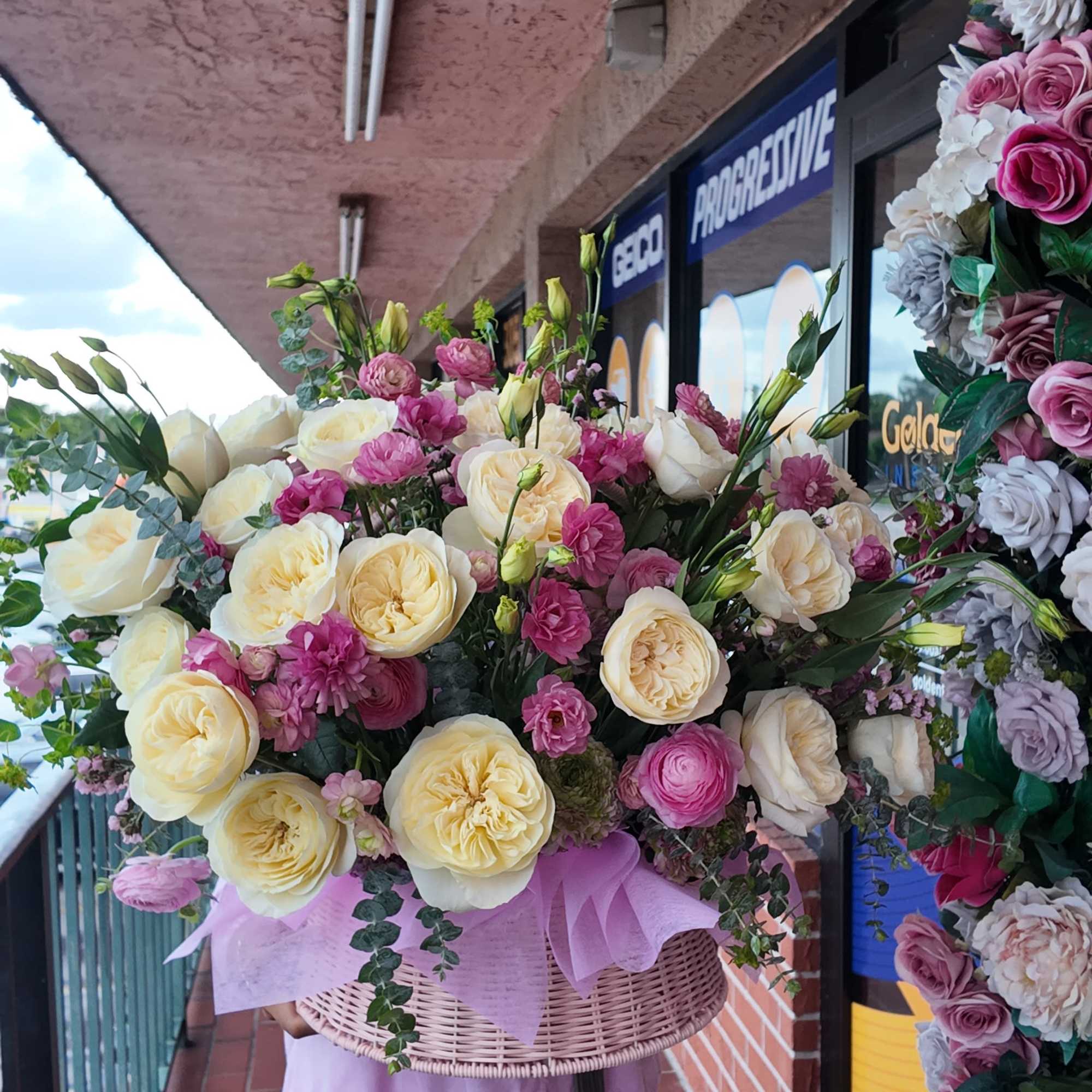 Large basket arrangement of cream and pink roses with small pink blooms